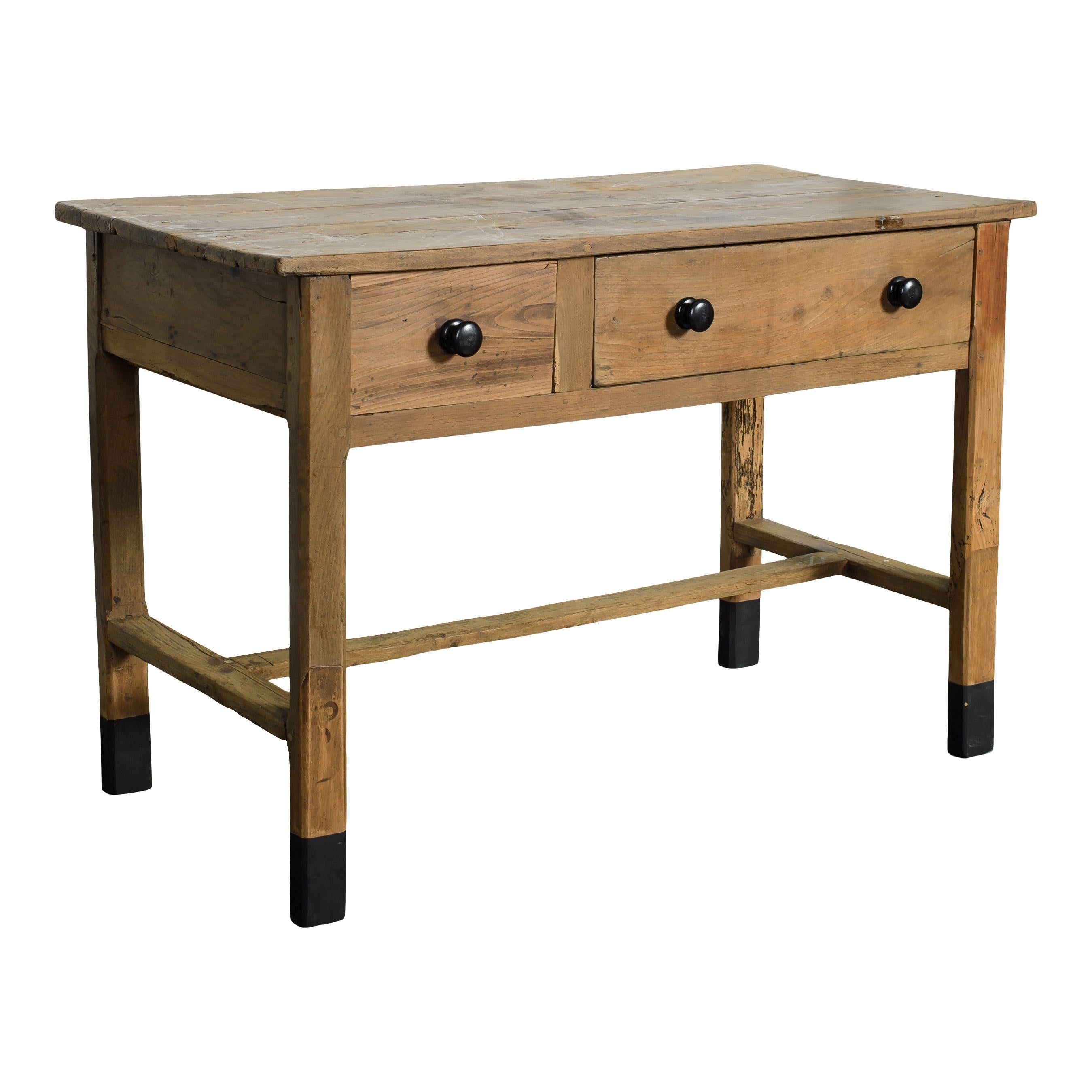 Una mesa holandesa vintage de madera con cajones. La parte superior y las patas son rectangulares y sencillas, lo que le confiere un estilo vintage atemporal. Hay un cajón pequeño y otro grande, ambos con pomos redondos de metal, y las patas son