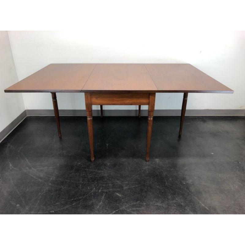 A Colonial style gateleg drop-leaf dining table by E A Clore & Sons of Madison, Virginia, USA. Solid walnut, a center apron and six turned legs, two being gateleg that swing out to support the drop leaves when raised. A very solid and sturdy table.