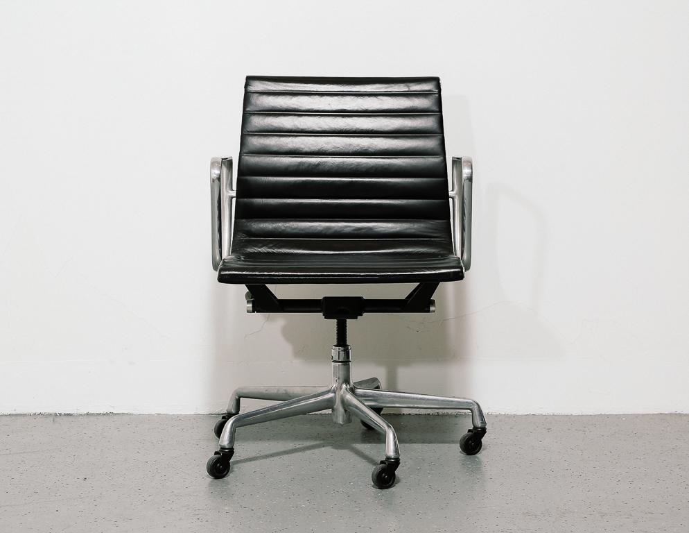 Eames for Herman Miller management chair. Black leather upholstery on aluminum frame. 5-star aluminum base on casters.