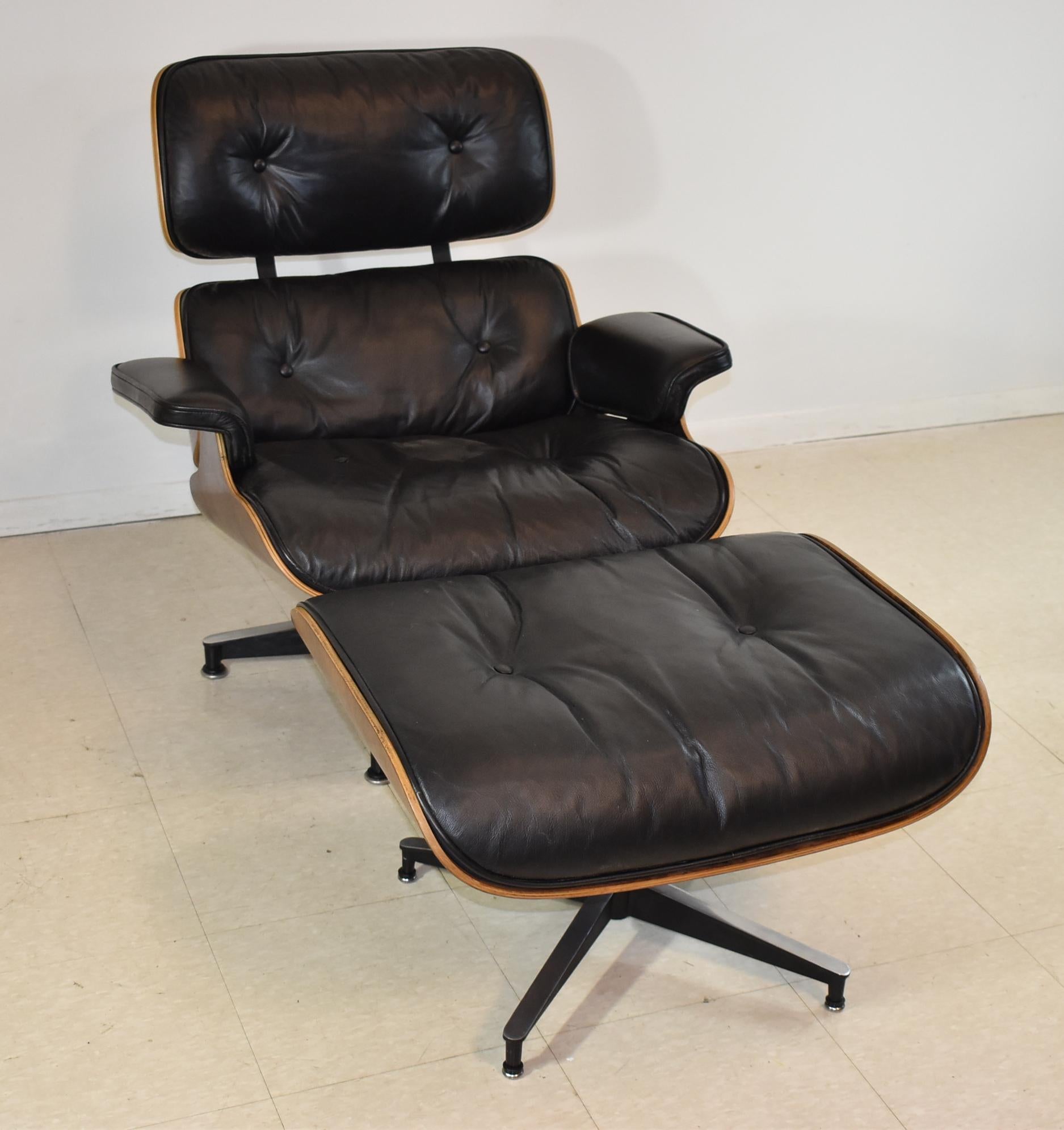 Vintage Eames black leather and rosewood chair and ottoman. Original finish. One button is loose.