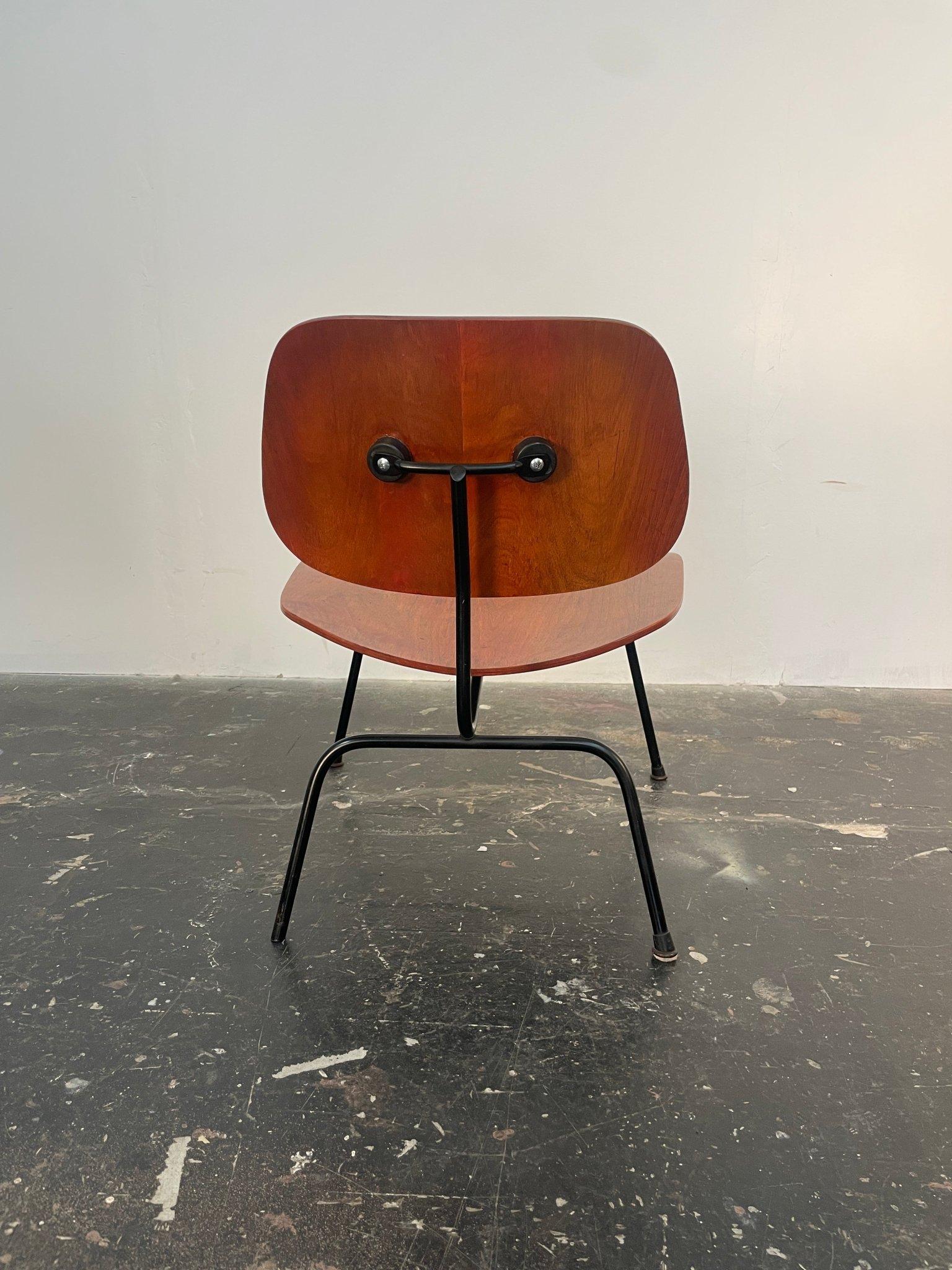 Charles and Ray Eames LCM (Lounge Chair Metal) by Herman Miller made of ash plywood in rare aniline Red, black enameled steel. Impressed mark to underside 'LCM'. Great patina on this piece. This chair is deceptively comfortable. Seat shock mounts in