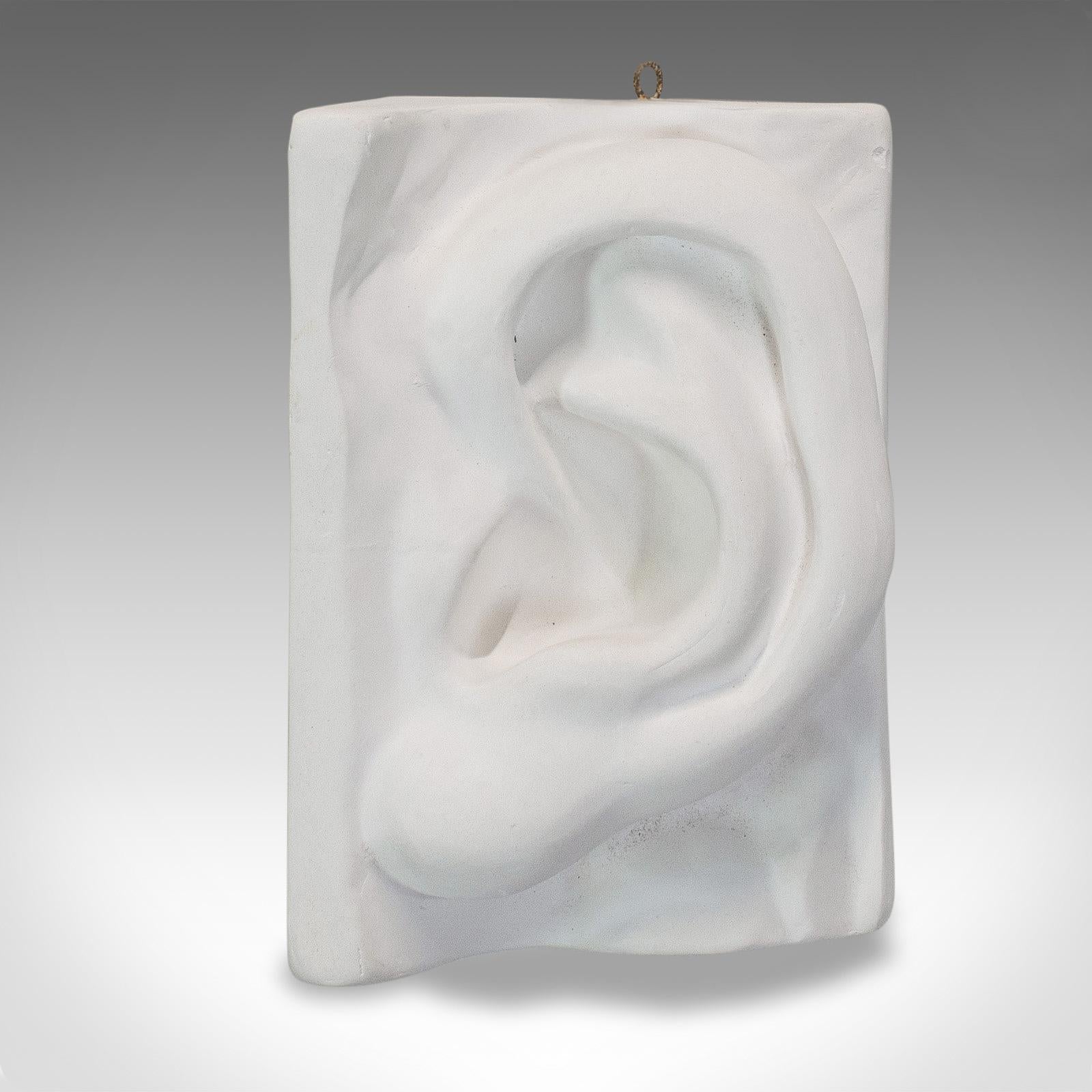 This is a vintage ear sculpture. An English, plaster cast haut relief anatomical portrait, dating to the late 20th century.

Unusual form and subject
Displays a desirable aged patina
Anatomical ear makes for a conversation piece
Replete with