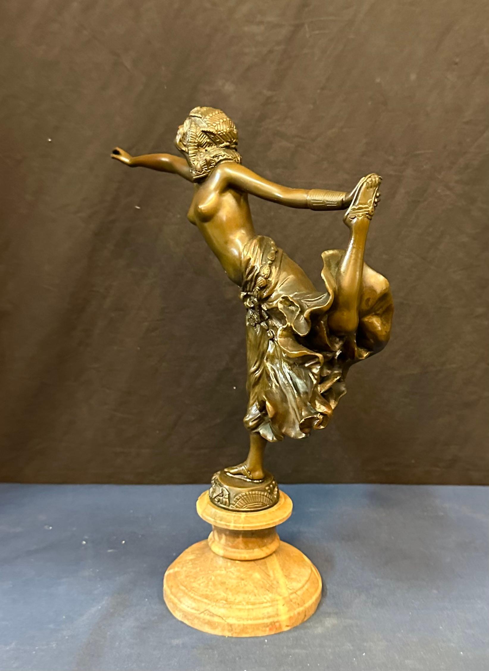 This vintage Continental (French) bronze sculpture dates from the early 20th century. It features a partially nude exotic Egyptian dancer posed with outstretched arms & one hand holding her high kicking foot. The beautifully patinated sculpture is