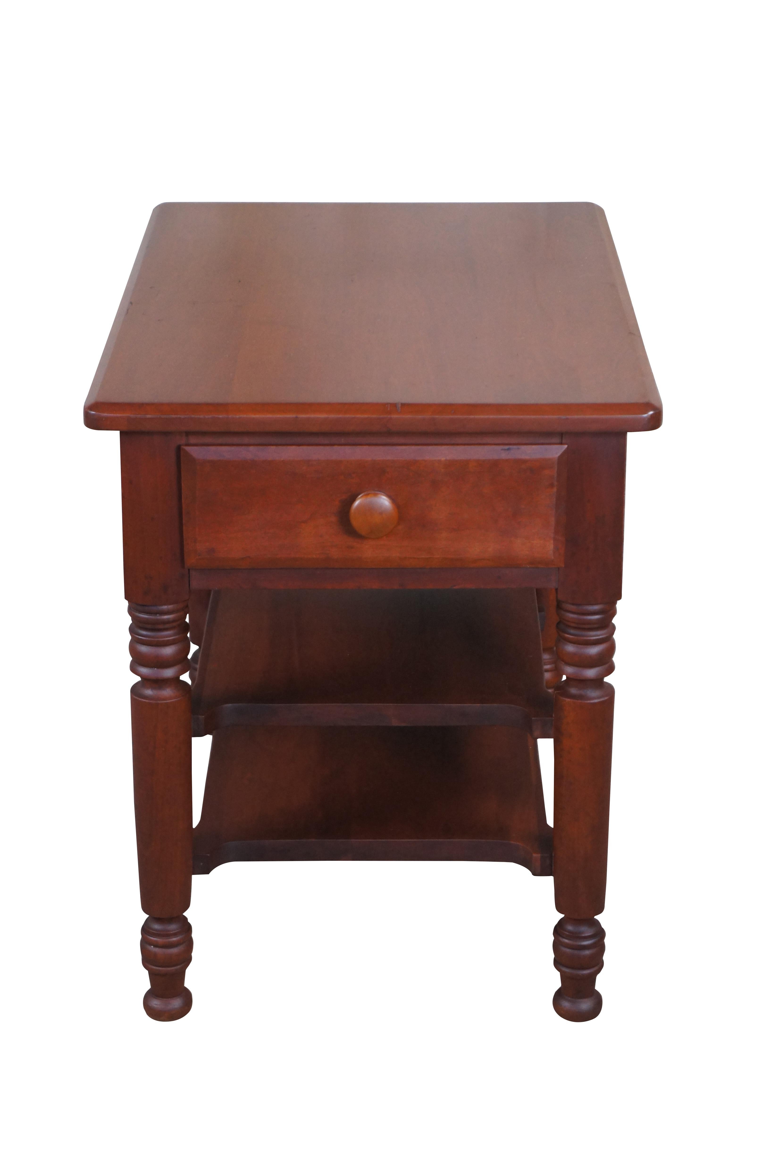 A beautiful solid cherry side table by The Sampler out of Homer, Indiana. Circa 1970s.  Features a rectangular form with a dovetailed drawer within the frieze over turned and ribbed legs with two tiers.  The legs taper into a turnip style foot. 