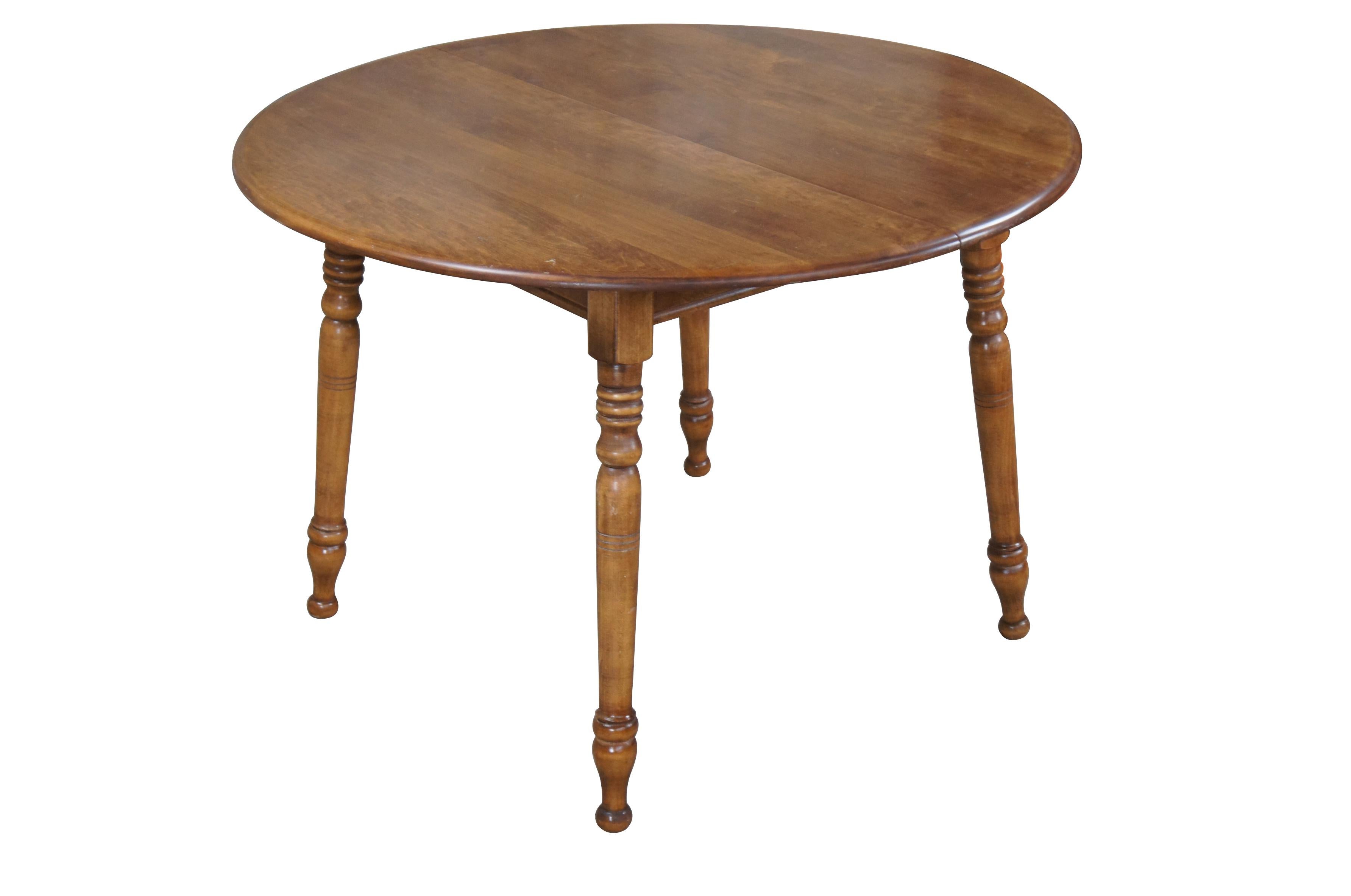 Early American style round dining table, circa second half 20th century.  Made from maple with turned legs leading to toupie feet.  Features two leaves allowing for expansion up to 66