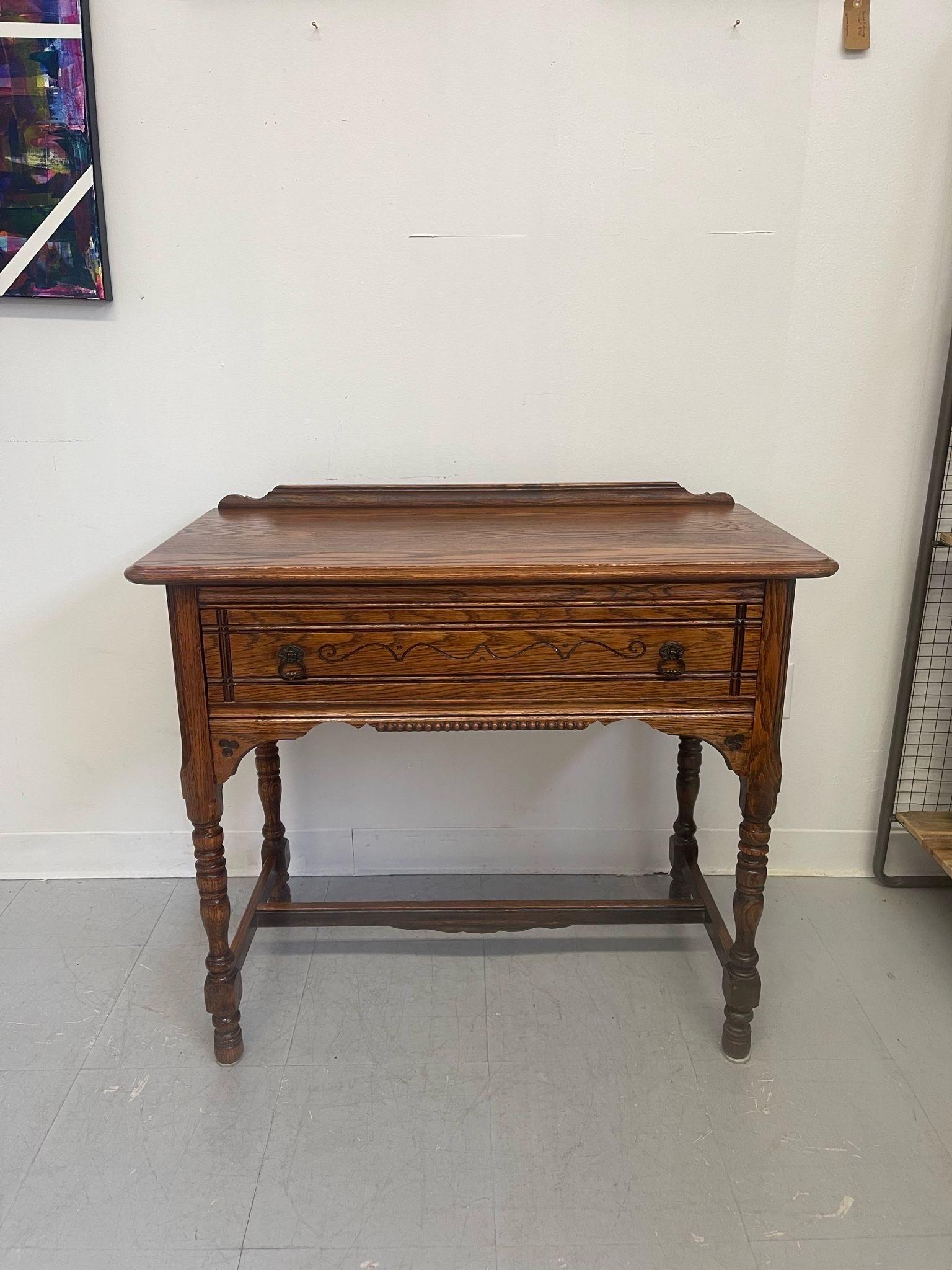 This piece features wood turned legs, original hardware, wood carved detailing, and a dovetailed drawer. The top piece is removable and has matching wood carved details. The detailing on the front of the drawer is unique.Early American Style lines
