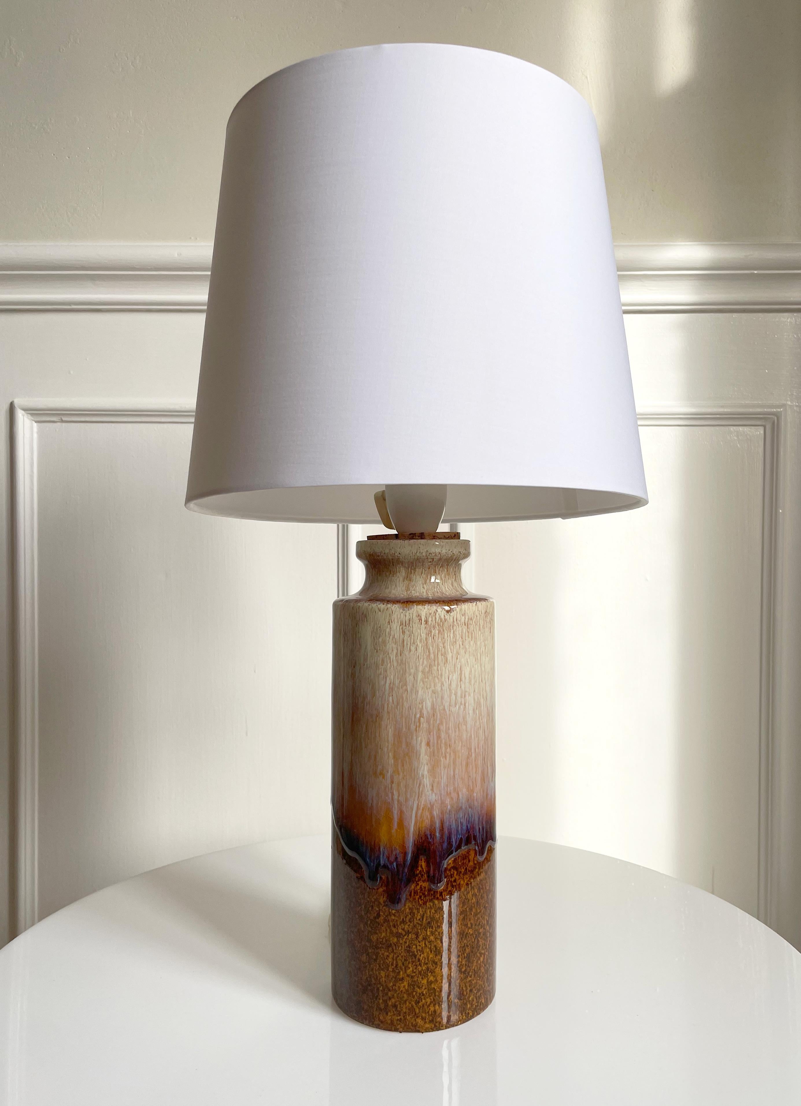 Lampe de table en céramique moderne du milieu du siècle, fabriquée à la main, avec une glaçure brillante de couleur terre dans les tons sable, terre d'ombre, violet et marron. La hauteur indiquée comprend le support d'abat-jour. L'abat-jour n'est