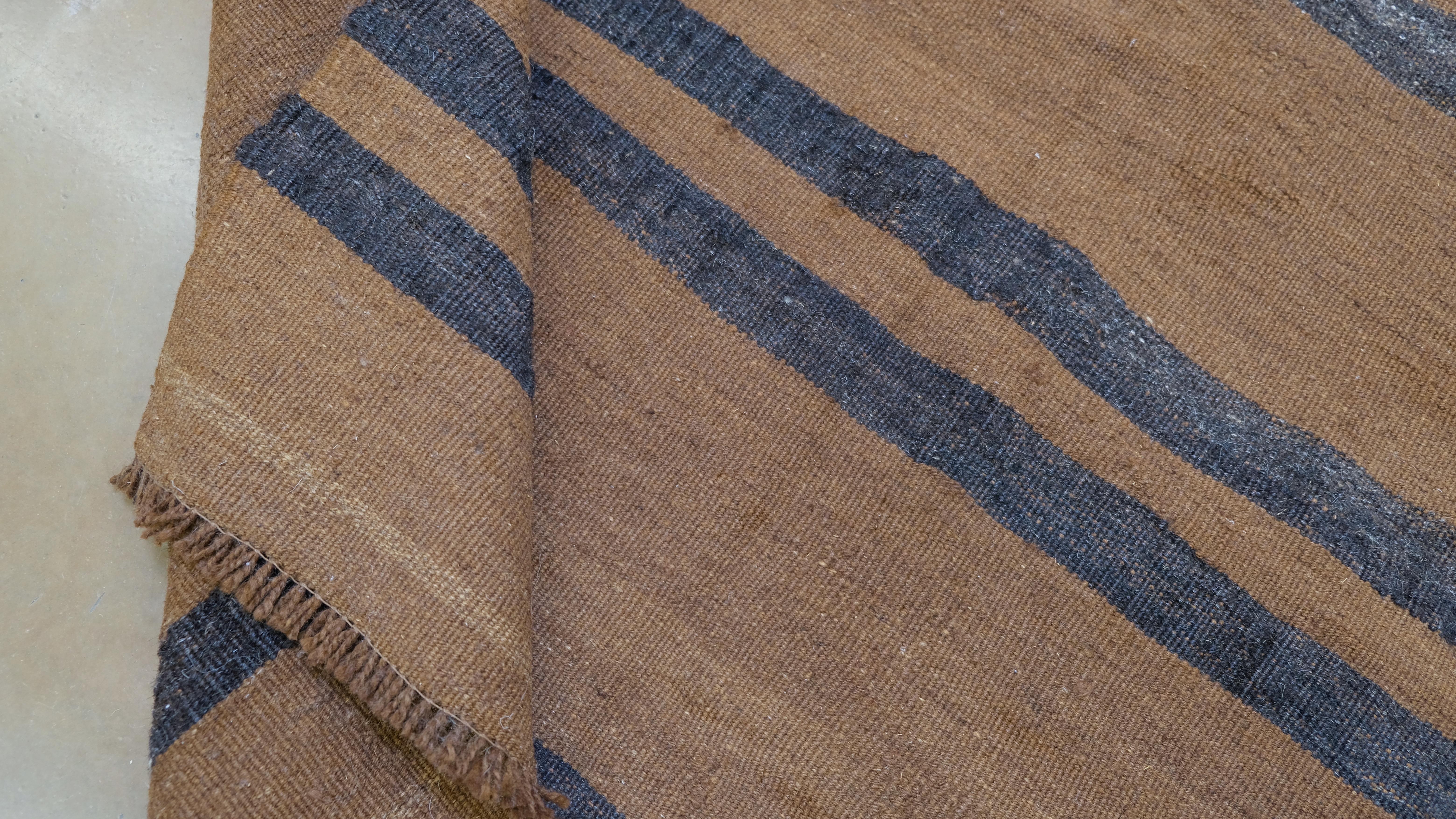 Elevate your interior with the understated charm of this vintage hand-knotted wool rug from Turkey. Featuring a minimalist striped design in earthy brown with contrasting charcoal grey accents, this rug embodies the essence of rustic elegance and