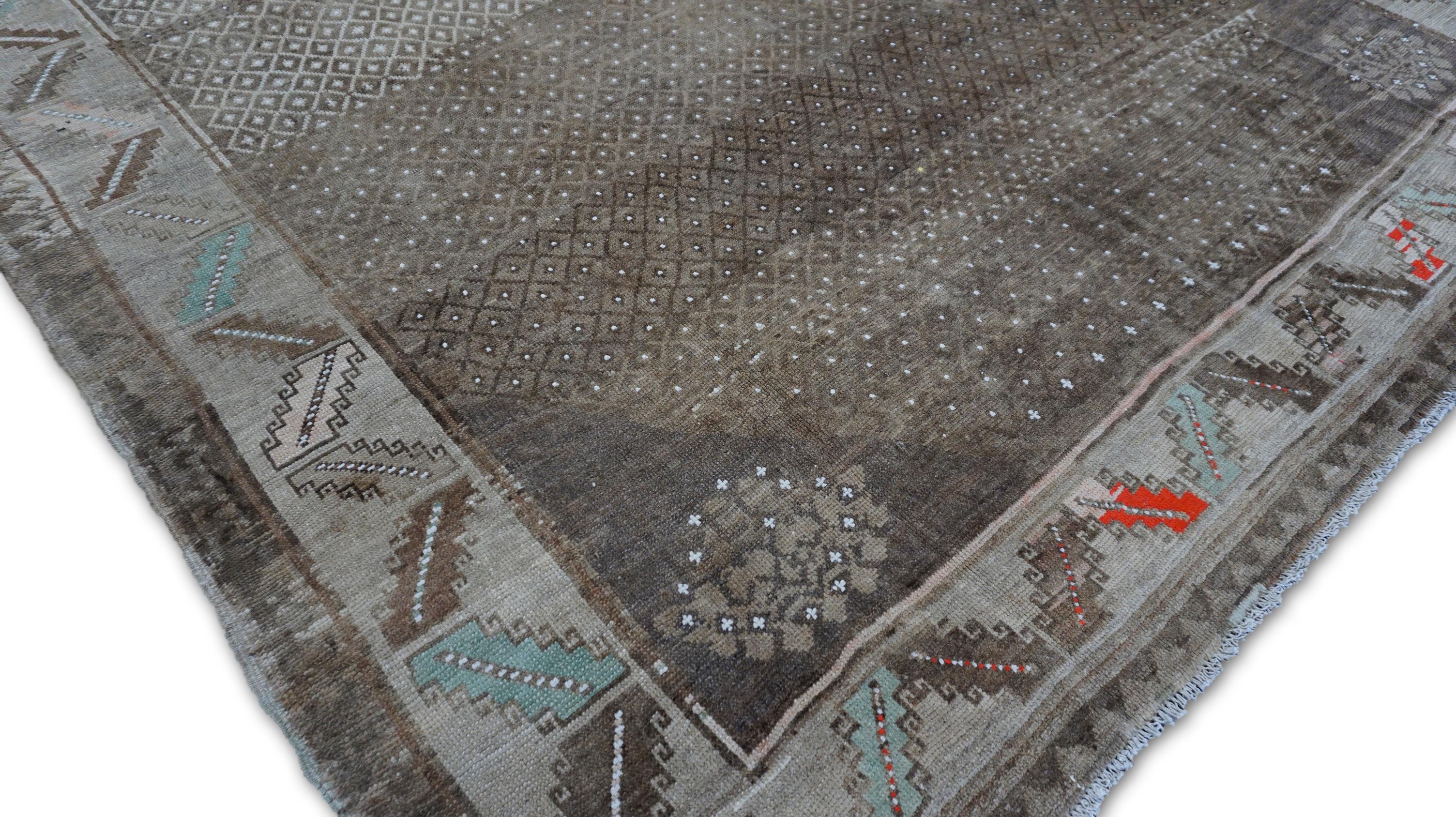 Dieser handgeknüpfte Wollteppich im Vintage-Stil ist ein seltenes und symbolträchtiges Stück mit einem unverwechselbaren Stammesmotiv in einer modernen, neutralen Farbpalette. Umrahmt von einer kühnen geometrischen Bordüre mit Zickzack- und