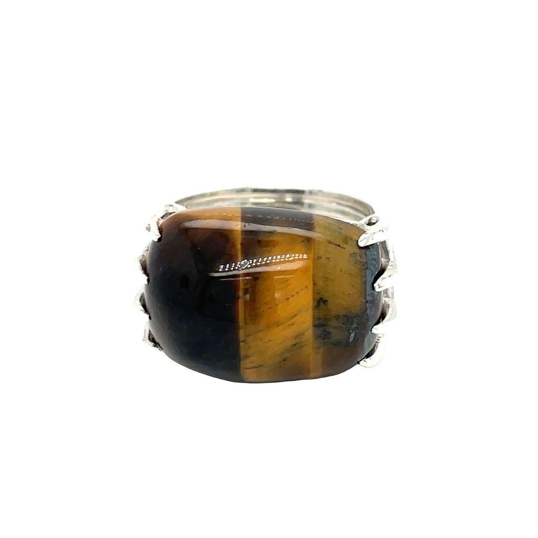 This silver dome ring features a hand-carved tiger's eye stone that glows beautifully. The large tiger's eye cabochon stone is elegantly set in an east-west position with eight prongs and measures 19.9 mm by 14.6 mm. It is a Mexican Modernist piece