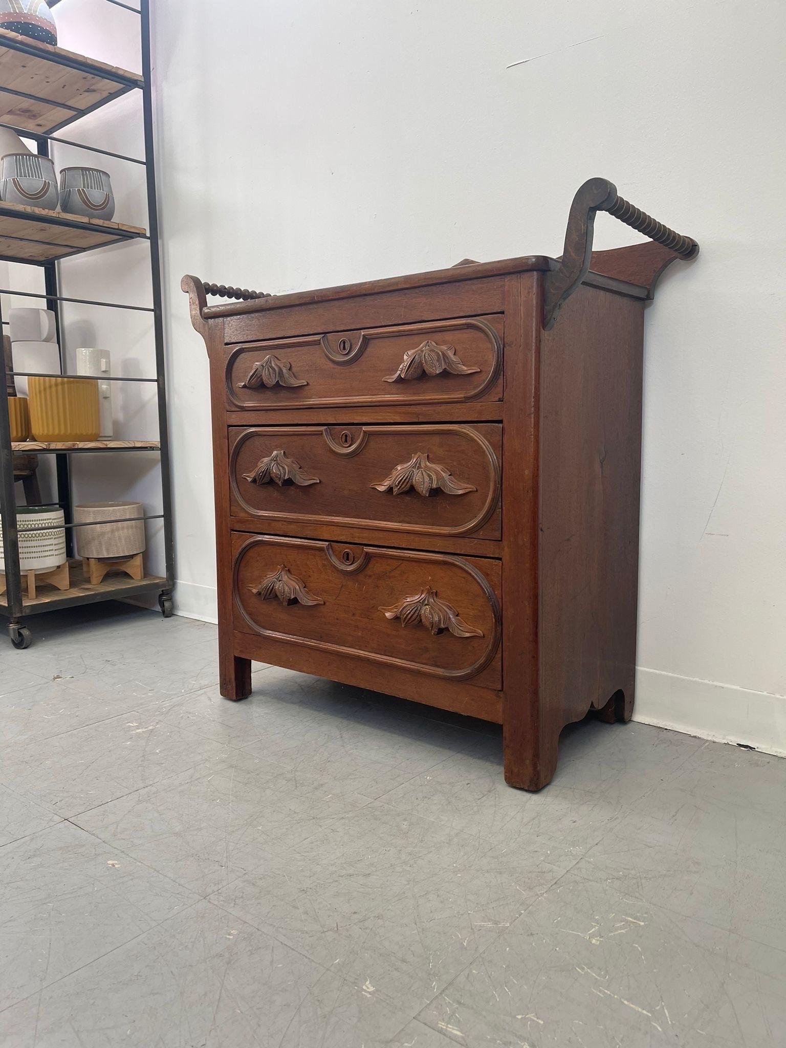 Possibly Circa 1860s.  This dresser has beautiful Walnut and leaf carved handles. Three hand cut dovetailed drawers. Appears to be hand panes. Wood carved details throughout. Vintage Condition Consistent with Age as Pictured. 

Dimensions. 36 W ; 16