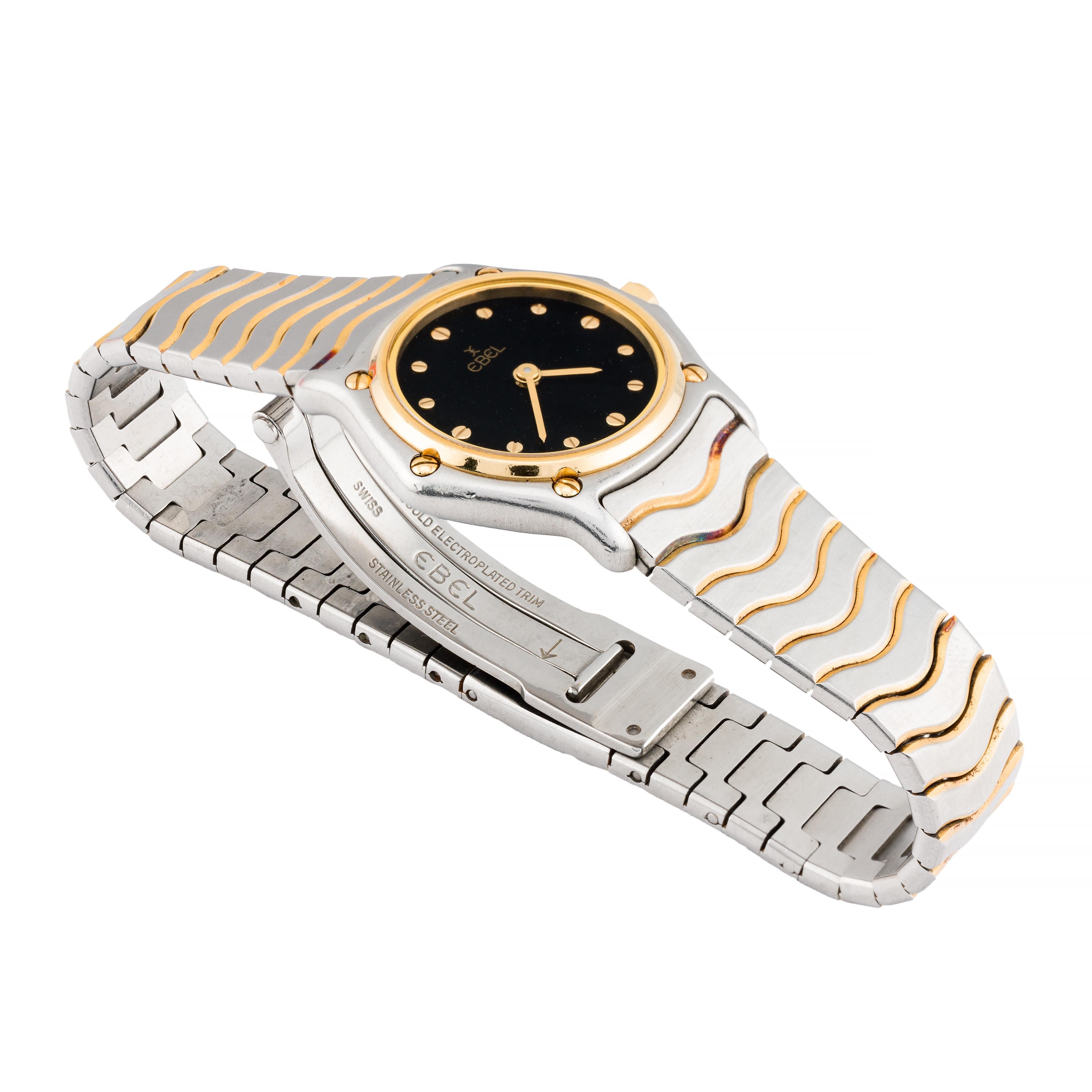 Aston Estate Jewelry Presenta:

Un distinguido reloj de pulsera Ebel fabricado en oro de 18 quilates y acero inoxidable.

El reloj redondo tiene una elegante esfera negra adornada con índices dorados. La firma Ebel aparece con elegancia, resaltando