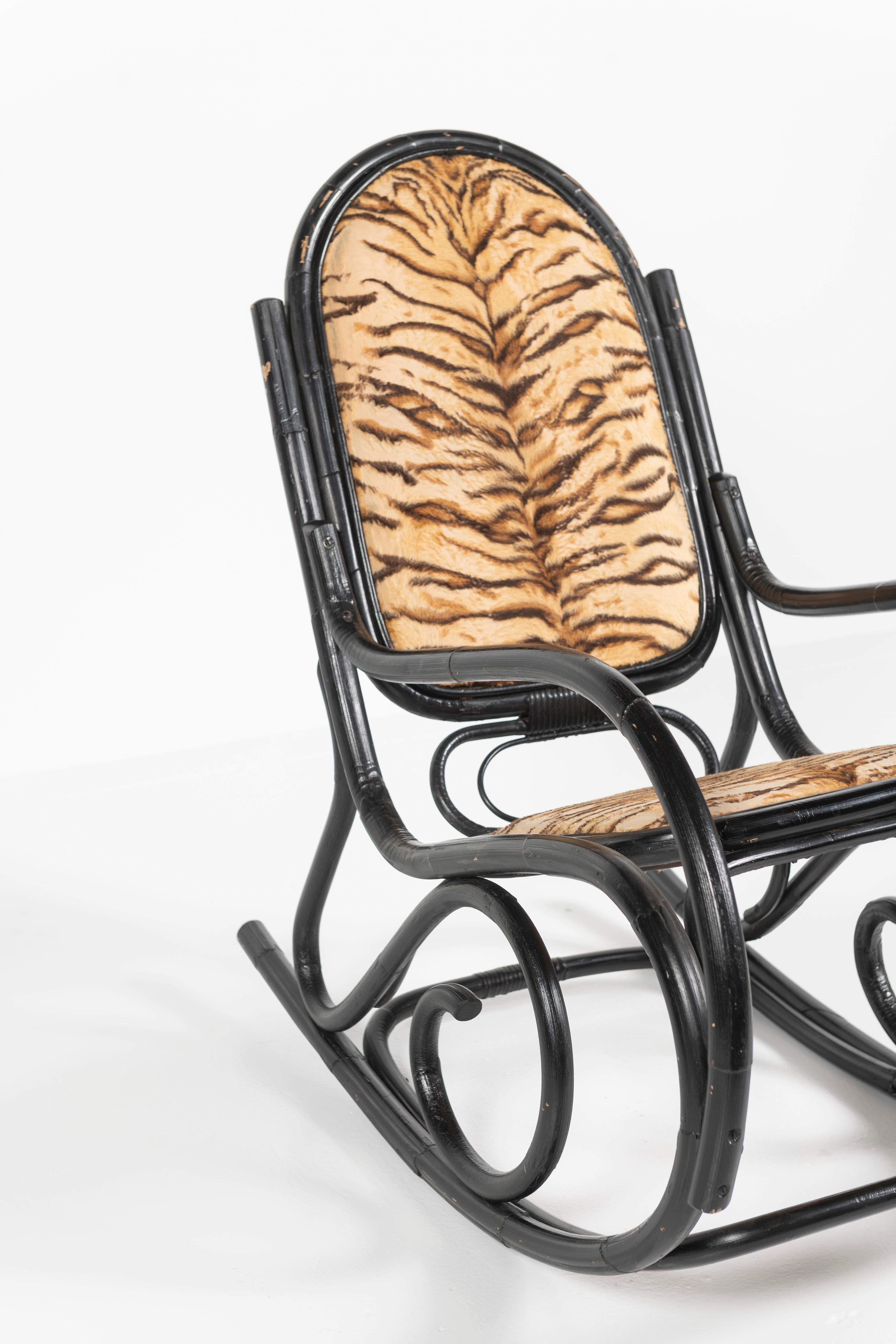This classic bentwood rocking chair. made of lacquered black bamboo, is attributed to Thonet from the 1920s. The seat interior and back have been upholstered in a tiger print fabric, likely replacing original cane seating. Comfortable for all the
