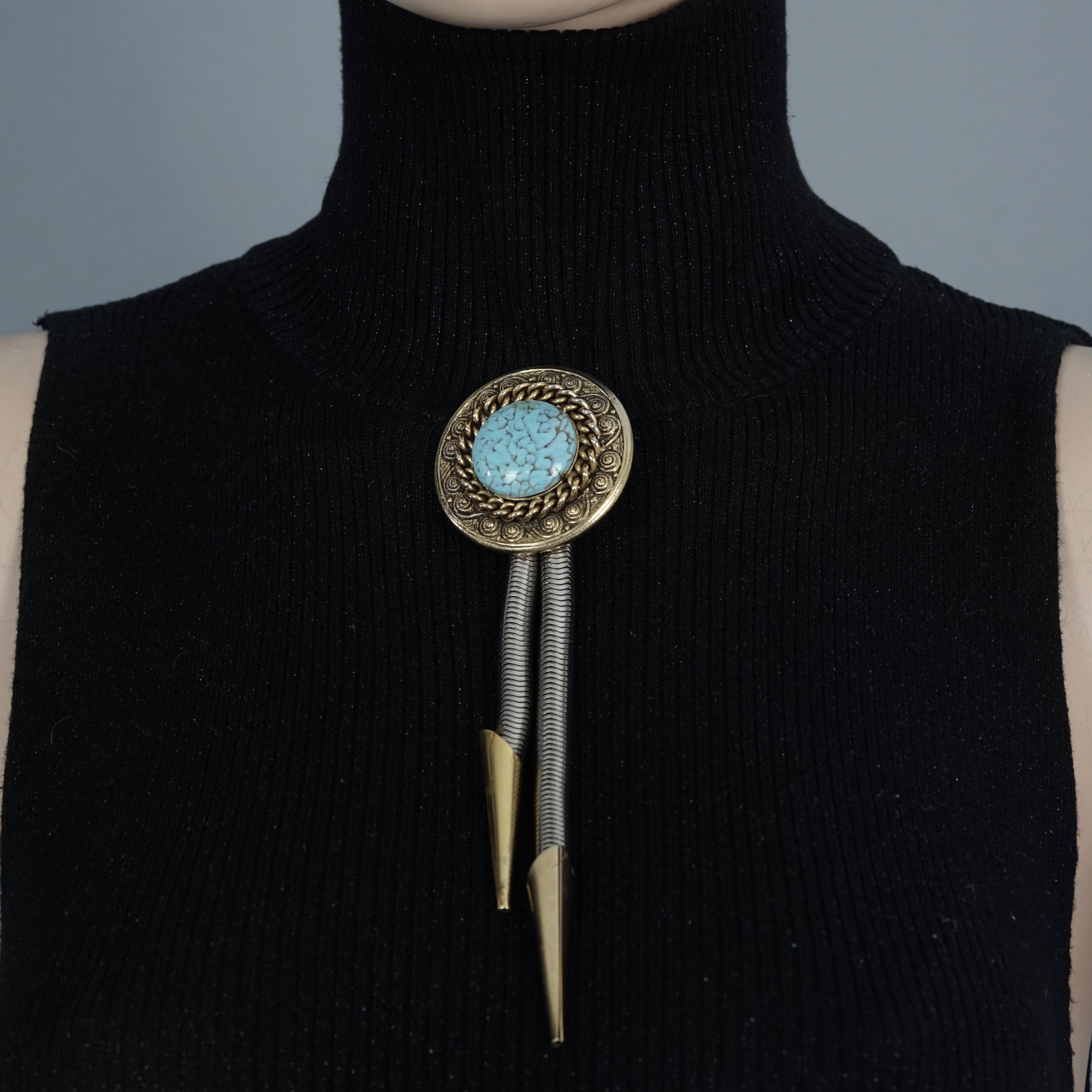 Vintage EDOUARD RAMBAUD Turquoise Medallion Bolo Tie Brooch

Measurements:
Height: 6.69 inches (17 cm)
Diameter Medallion: 1.92 inches (4.9 cm)

Features:
- 100% Authentic EDOUARD RAMBAUD PARIS.
- Wester bolo tie/ bootlace tie brooch with turquoise