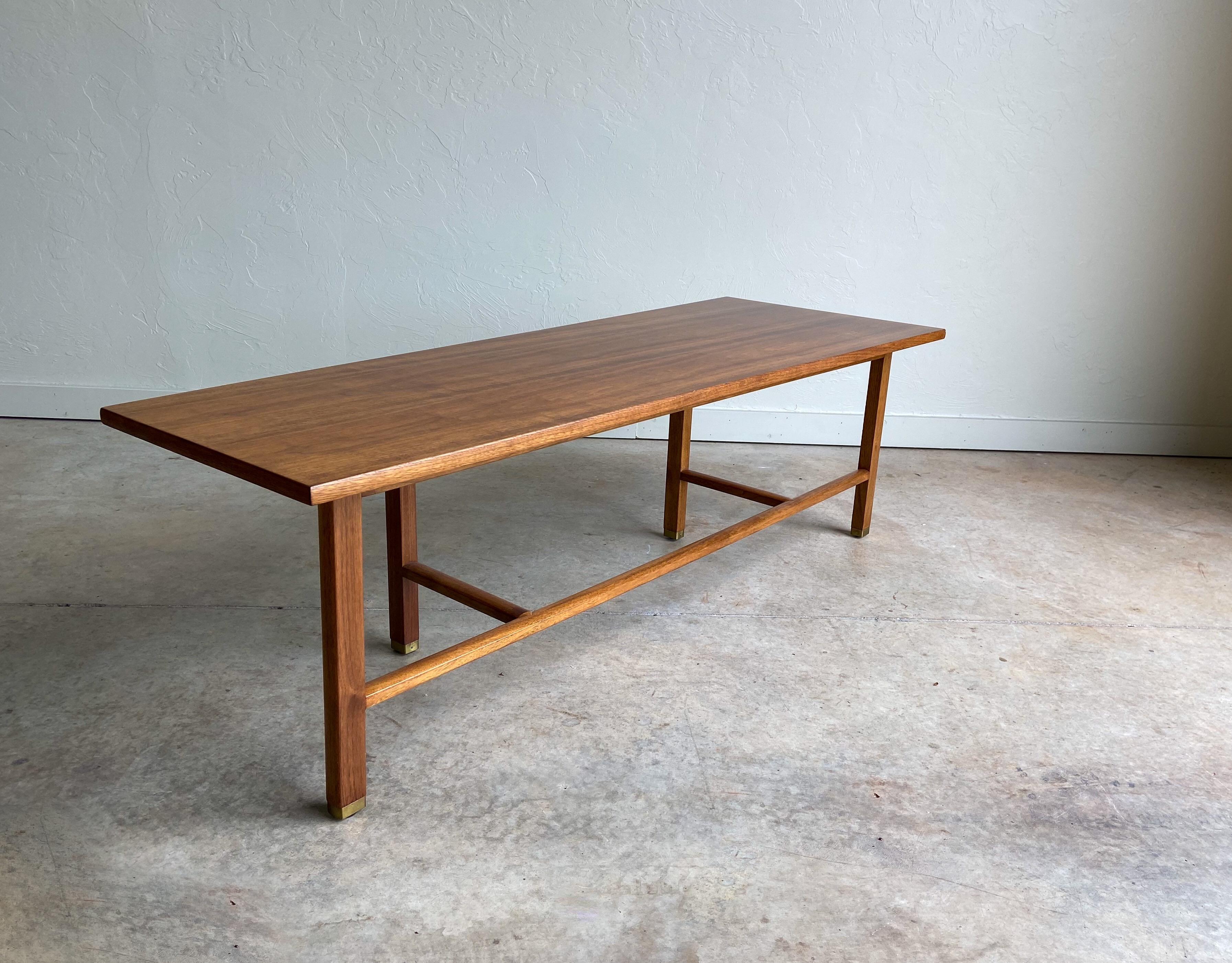 A walnut coffee table designed by Edward Wormley for Dunbar. A solid walnut base with brass capped feet supports a walnut veneer top with a beautiful grain. Original Dunbar label present.

 