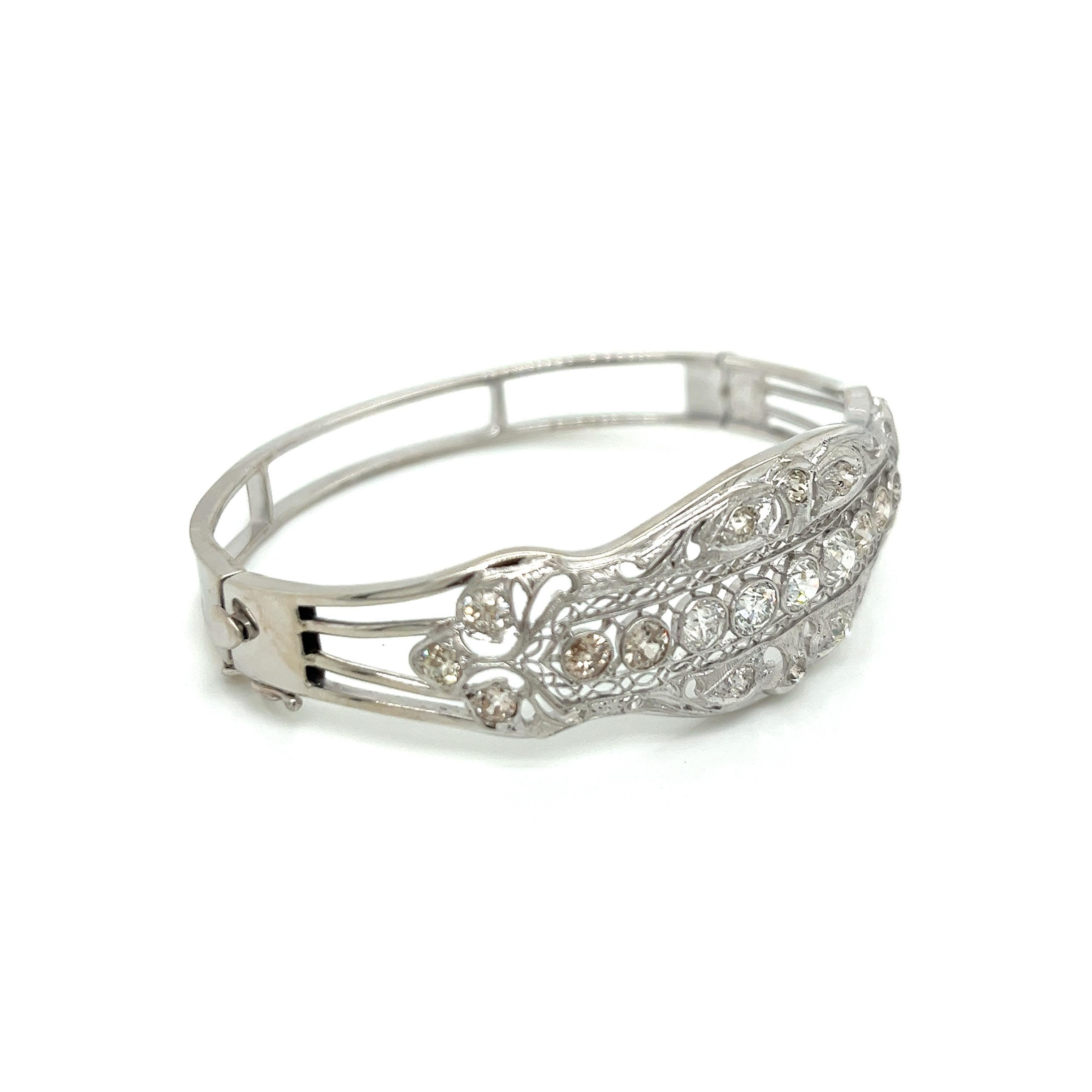 This is a magnificent vintage Edwardian platinum and 14k white gold diamond filigree bangle bracelet, a true testament to the exquisite craftsmanship of its era. The top section features an intricate platinum filigree design adorned with 21 stunning
