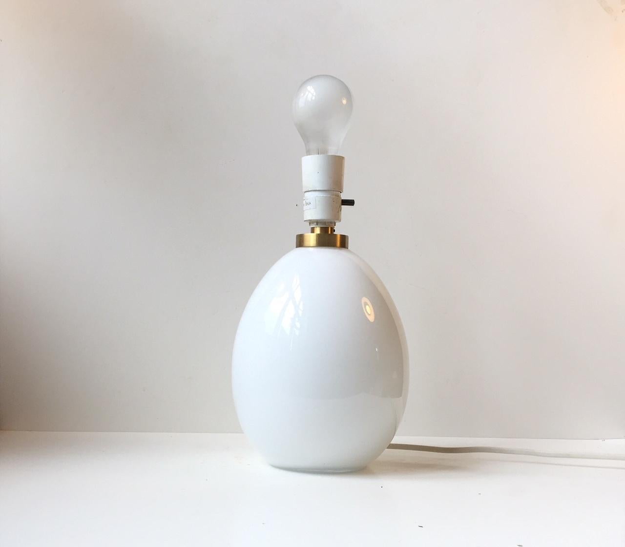 This egg-shaped white opaline glass table lamp was designed by Poul Seest Andersen and manufactured by Le Klint in Denmark during the late 1970s or early 1980s. It features a pin-on/off switch, a brass top and the maker's mark to the base. Please