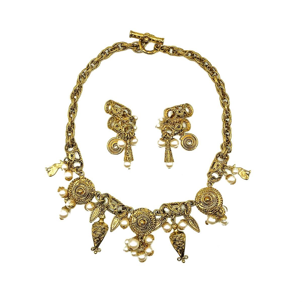 A wonderfully intricate and impactful Vintage Egyptian Charm Necklace with matching statement earrings. Featuring heavily embellished design elements inspired by Egyptian design and motifs. The lustrous gold setting off the creamy pearls to