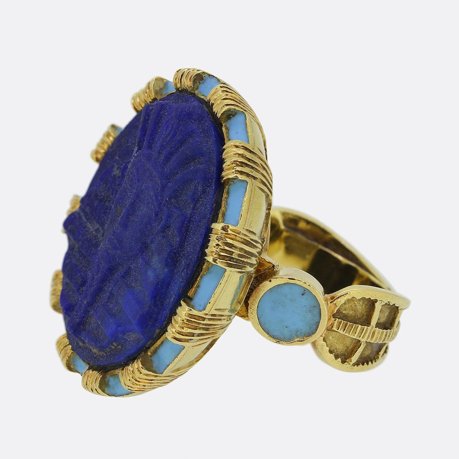 Here we have a vintage 18ct yellow gold Egyptian revival ring. The face of the piece showcases a carved lapis lazuli featuring Tutankhamun's head. Surrounding the Lapis there is a turquoise blue enamel border and a carved gold shank. The ring is a