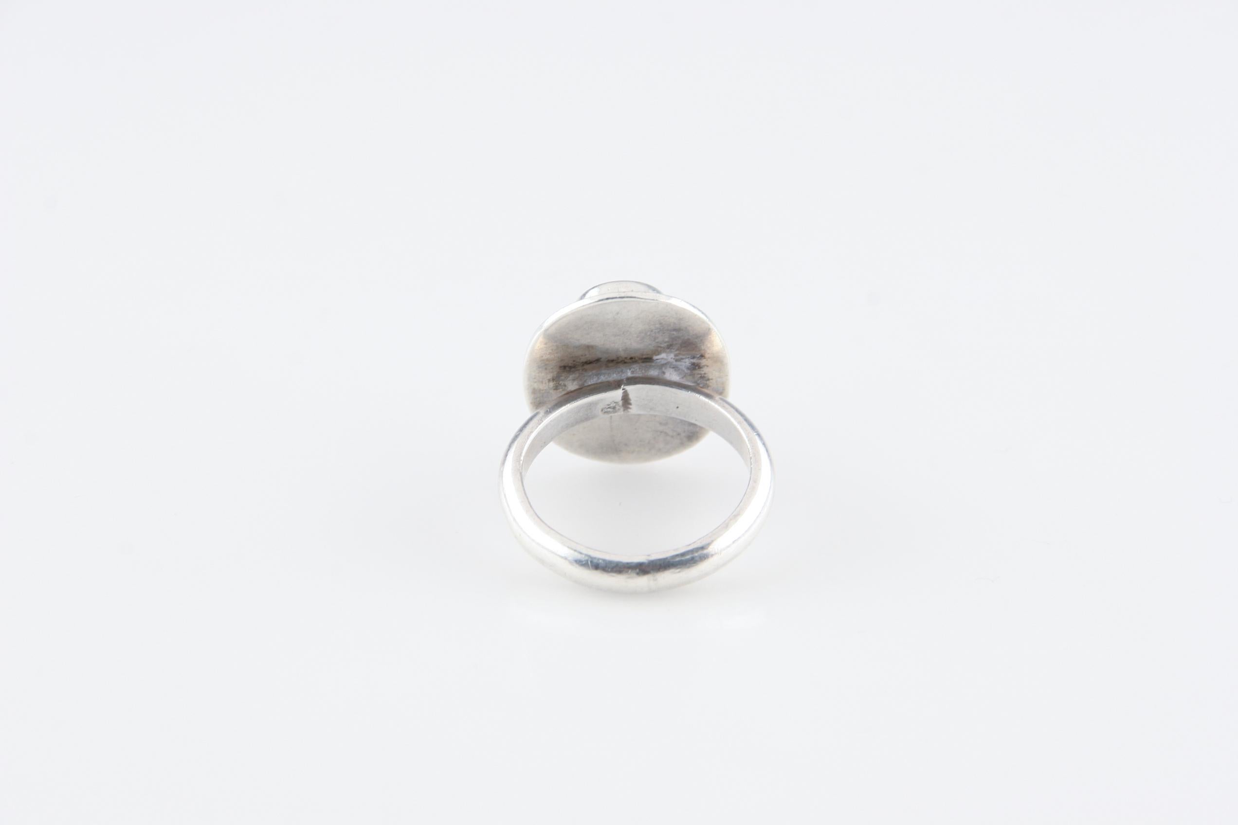 This ring is composed of an oval-shaped natural turquoise stone set within a silver bezel.
The design of the ring appears simple, but has an elegance in it's simplicity.

Size: 8.
Weight: 9.0 grams.
Metal: 0.800 silver.
Features: