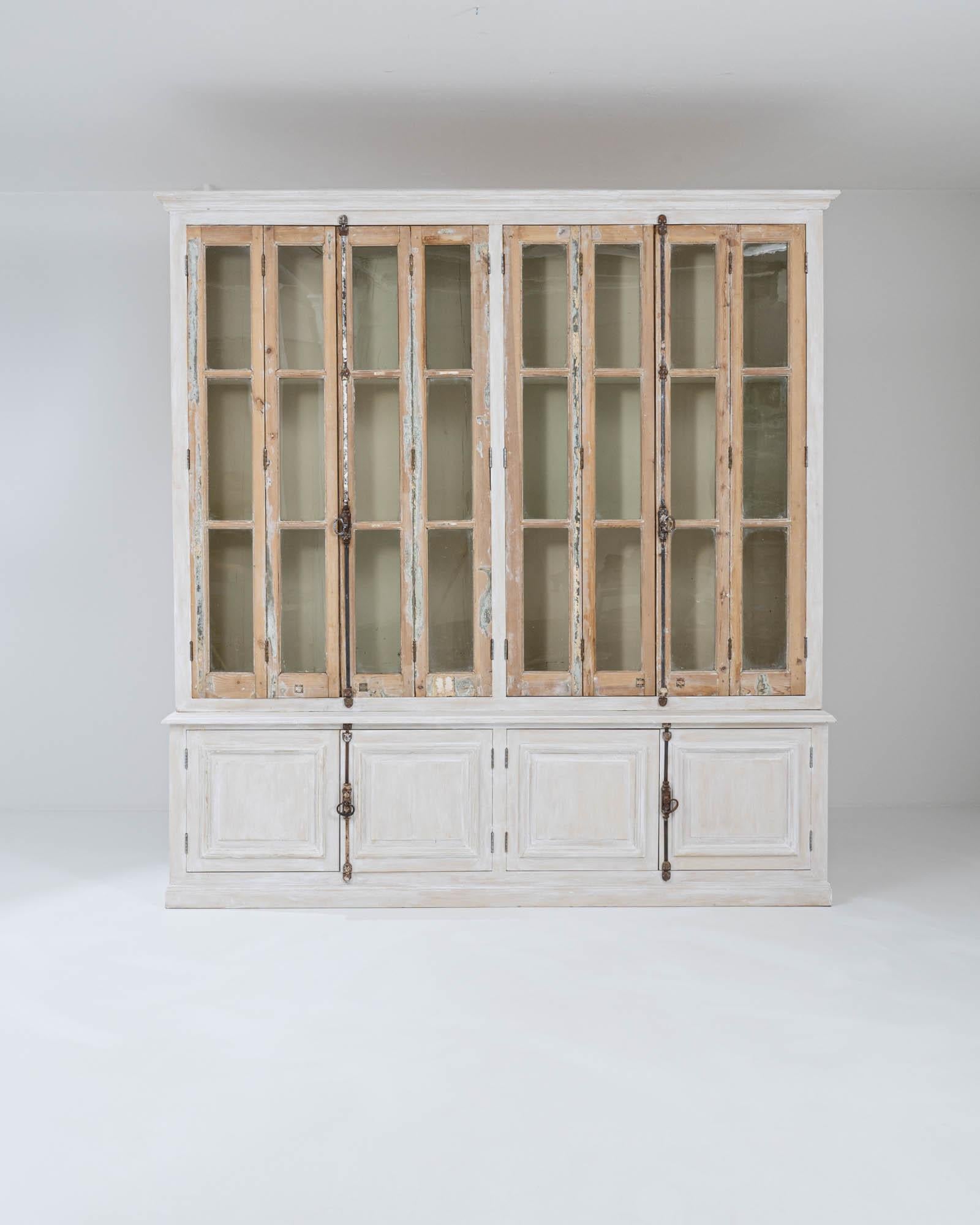 An interplay of patinas gives this vintage wooden vitrine a unique and intriguing personality. Made in Northern Africa, the handsome cabinet with its carved cornice and deep paneling is painted a shade of clean white, muted and faded by a patinated