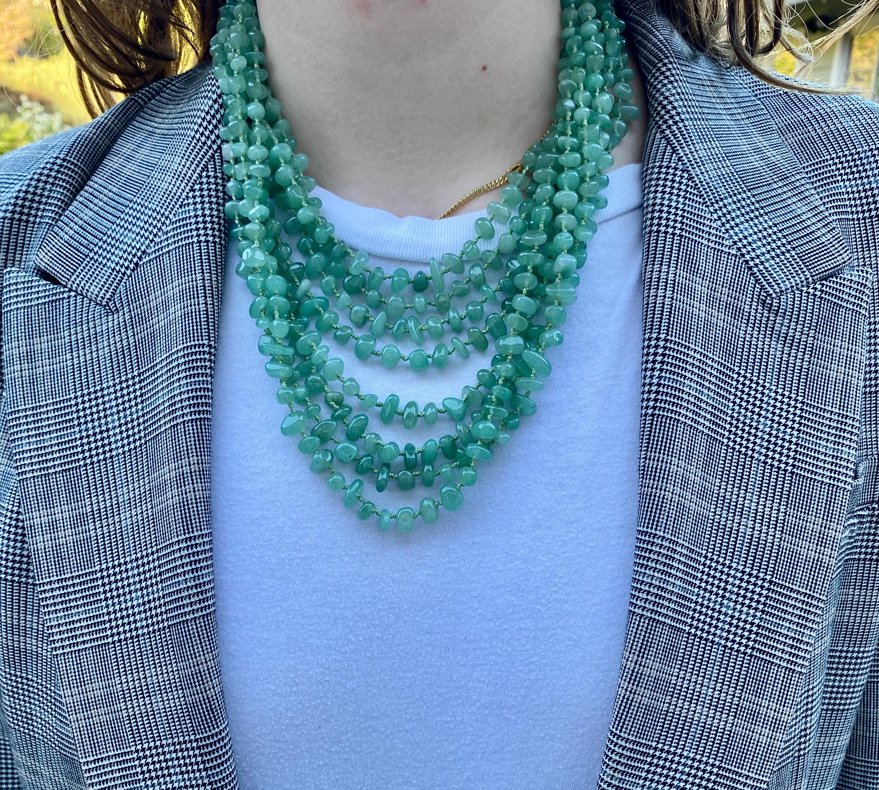 Eine dramatische, achtsträngige Halskette mit zeladongrünen Aventurin-Perlen, die einzeln auf grünem Seidenfaden mit einem Aventurin-Verschluss geknüpft sind.

Die acht abgestuften Stränge variieren in der Länge, wobei der kürzeste etwa 43 cm (17