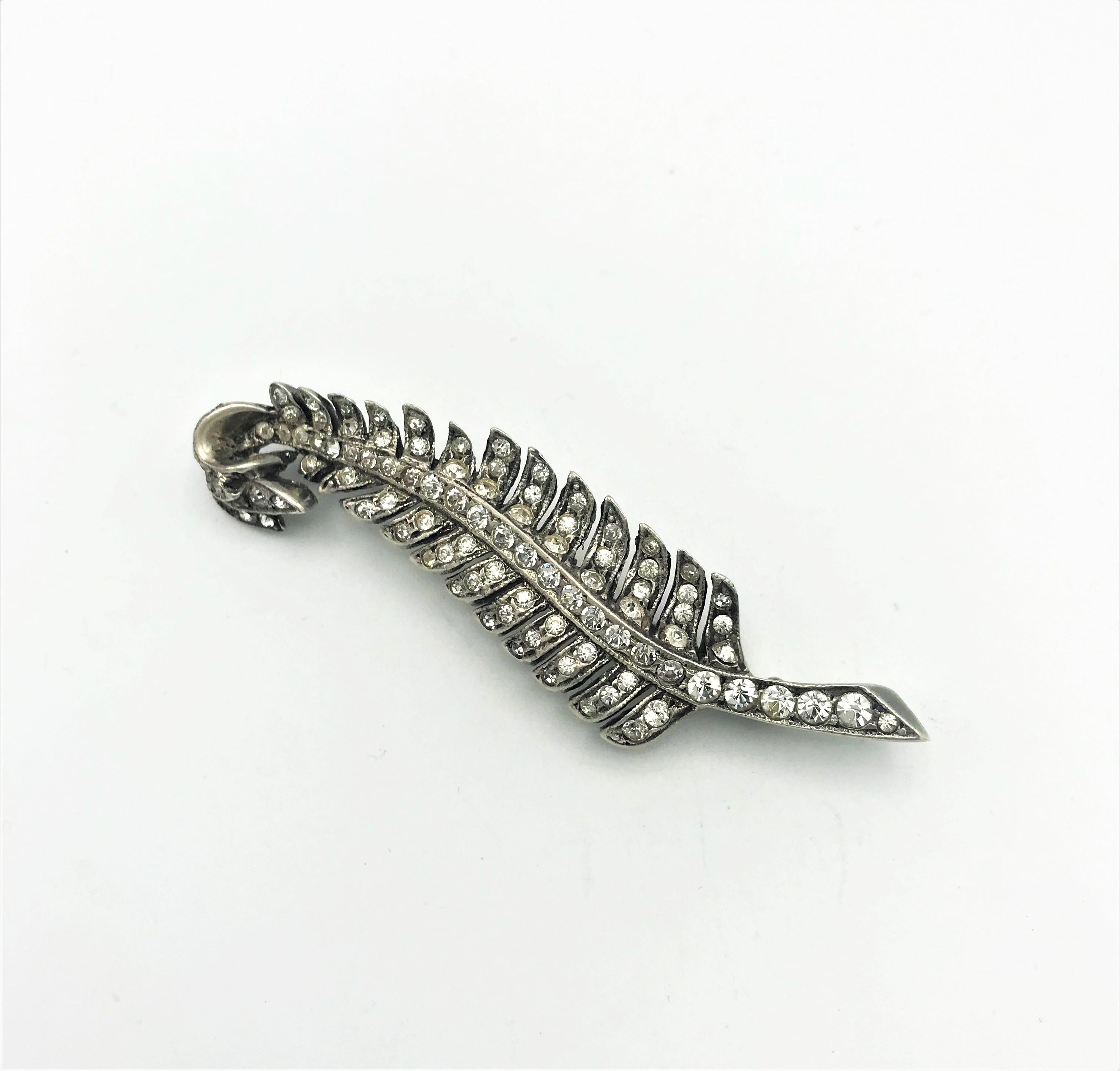 Eisenberg brooch in the shape of a feather with many rhinestones set in it. Stamped with E for Eisenberg and Sterling/ Back of the brooch.

Measurement: Hight 7 cm, wide 2 cm in vey good condition and a very nice goldsmith work! 