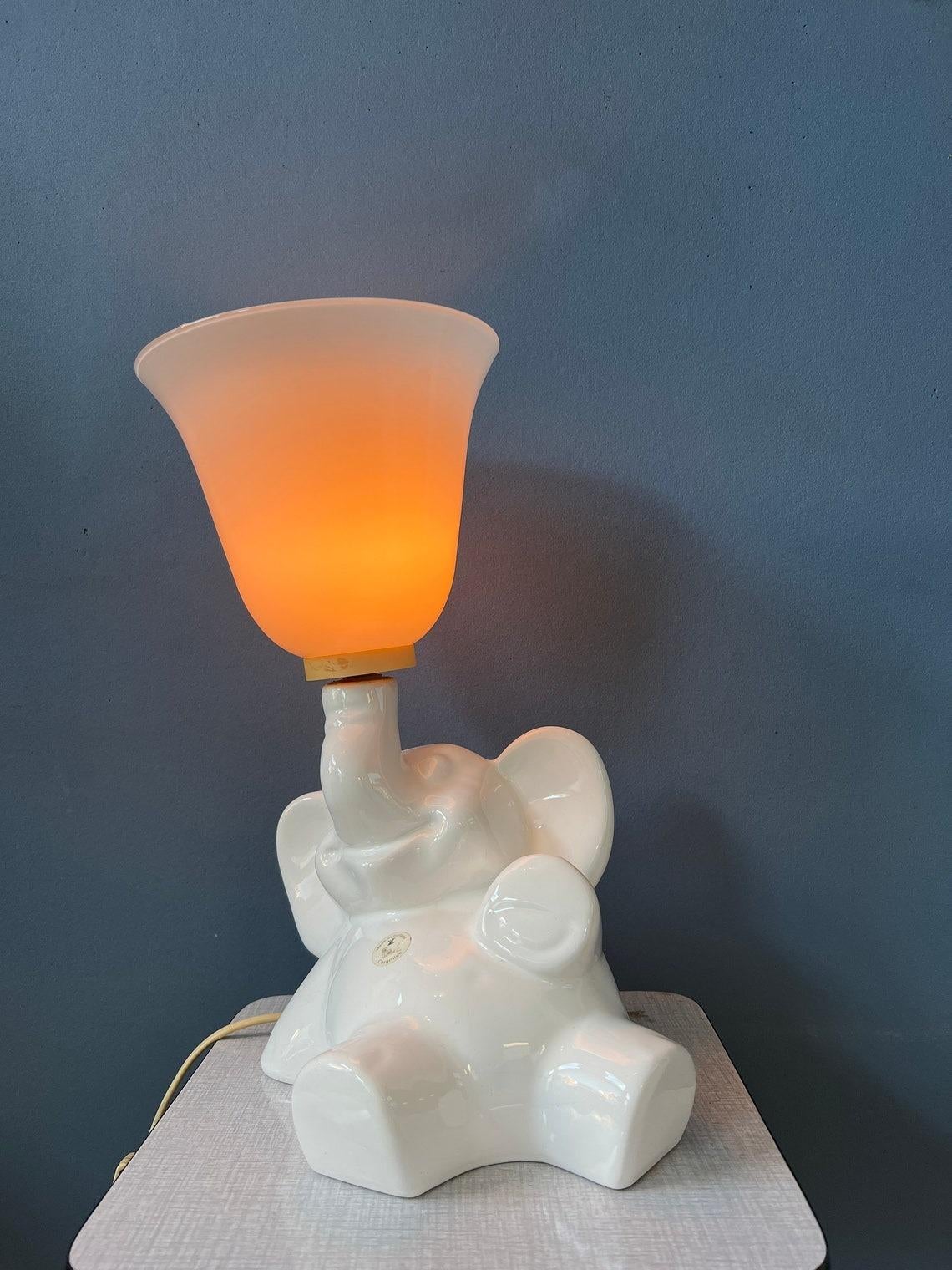 Rare lampe éléphant en porcelaine avec un abat-jour en verre. L'abat-jour en forme de corne peut être fixé à l'éléphant de porcelaine séparément. La lampe nécessite une ampoule E27 et dispose actuellement d'une fiche de connexion à