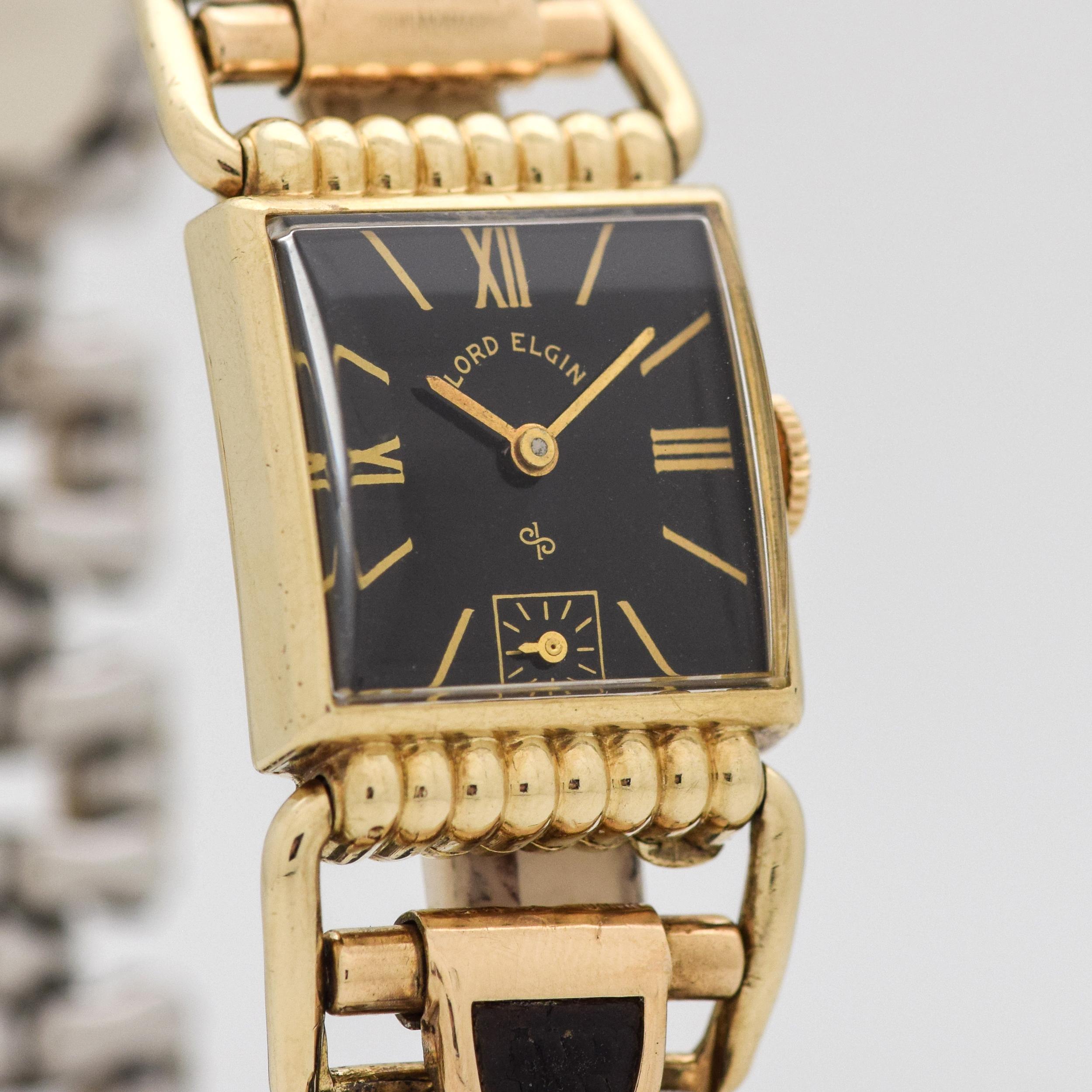 1952 Vintage Lord Elgin Driver's 14k Yellow Gold Filled watch with Original Black Dial with Gold Color Roman Numerals III/ IX, and XII with Time Period Correct Expandable Stretchy 12k Yellow Gold Filed and Black Lizard Skin Bracelet. 20mm x 45mm lug