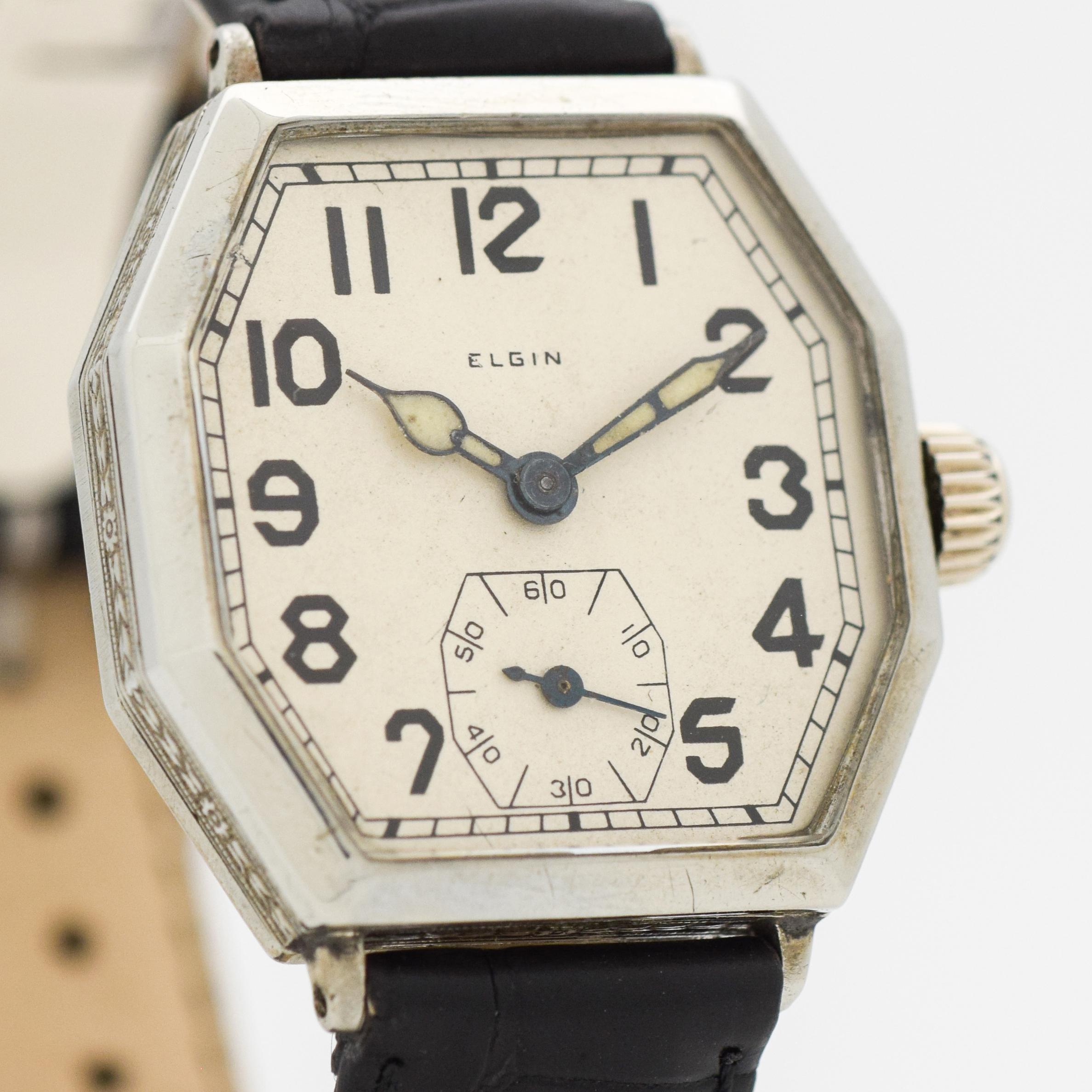 1928 Vintage Elgin watch. Octagonal/Stop-sign shaped case. Nickel. Original, but restored dial with black-colored Arabic numerals. Powered by a 9-jewel, manual caliber movement. Equipped with a matte, Black-colored Alligator watch strap. 30mm x 36mm