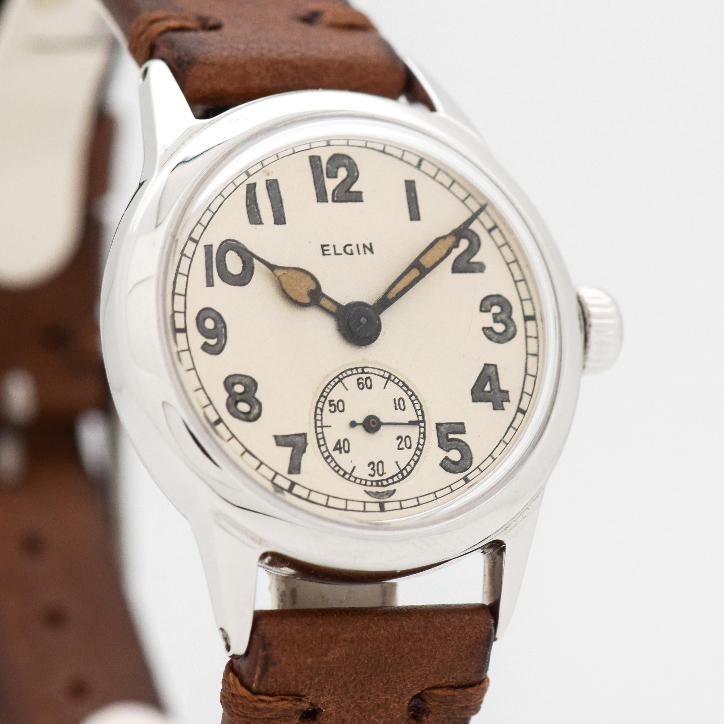 1944 Vintage Elgin WWII-era Military Watch. Base Metal case that measures in at 32mm wide. Original, but restored dial with Arabic numerals. Powered by a 17-jewel, manual caliber movement. US Military. 