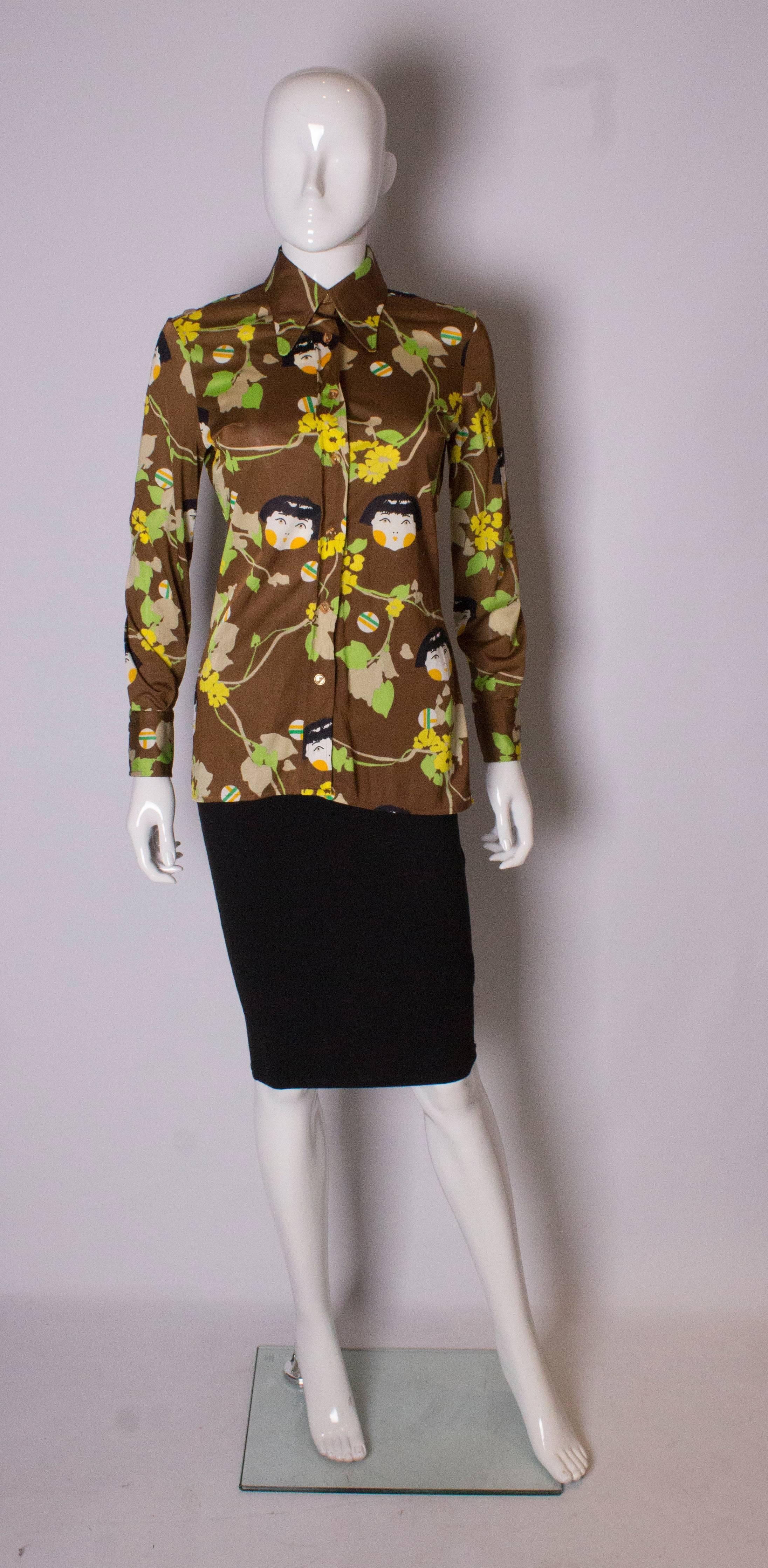 A great vintage  shirt by Elli, Europe Craft of Italy. The shirt is made of a textured nylon with double button cuffs. It has a brown background with a green and yellow, face and flora print.
