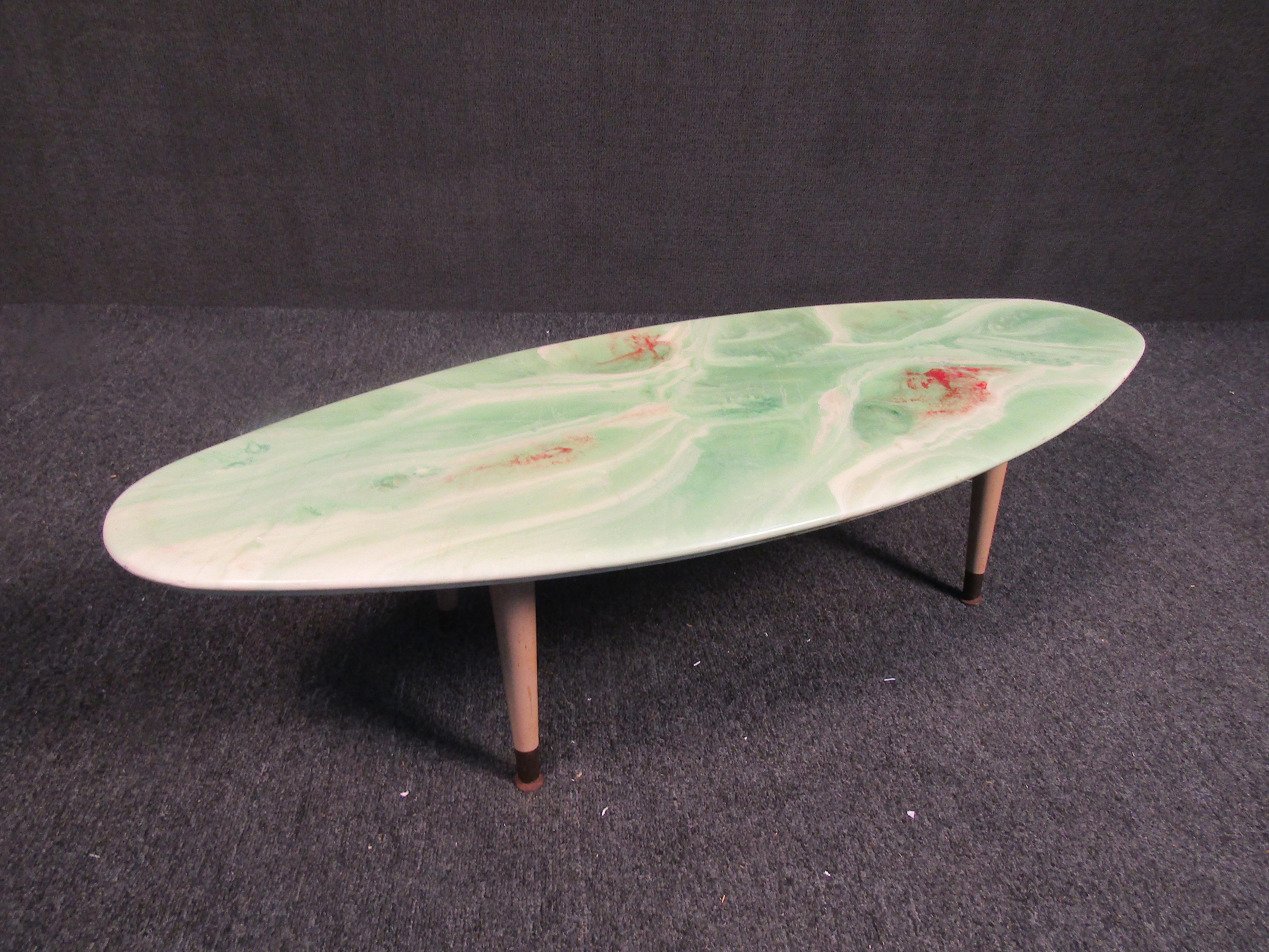 Mid-century resin elliptical table. Featuring a surfboard shaped appearance, red and green swirl surface and adjustable wooden legs. A very unique piece that would be an excellent addition to any living space.

(Please confirm item location - NY