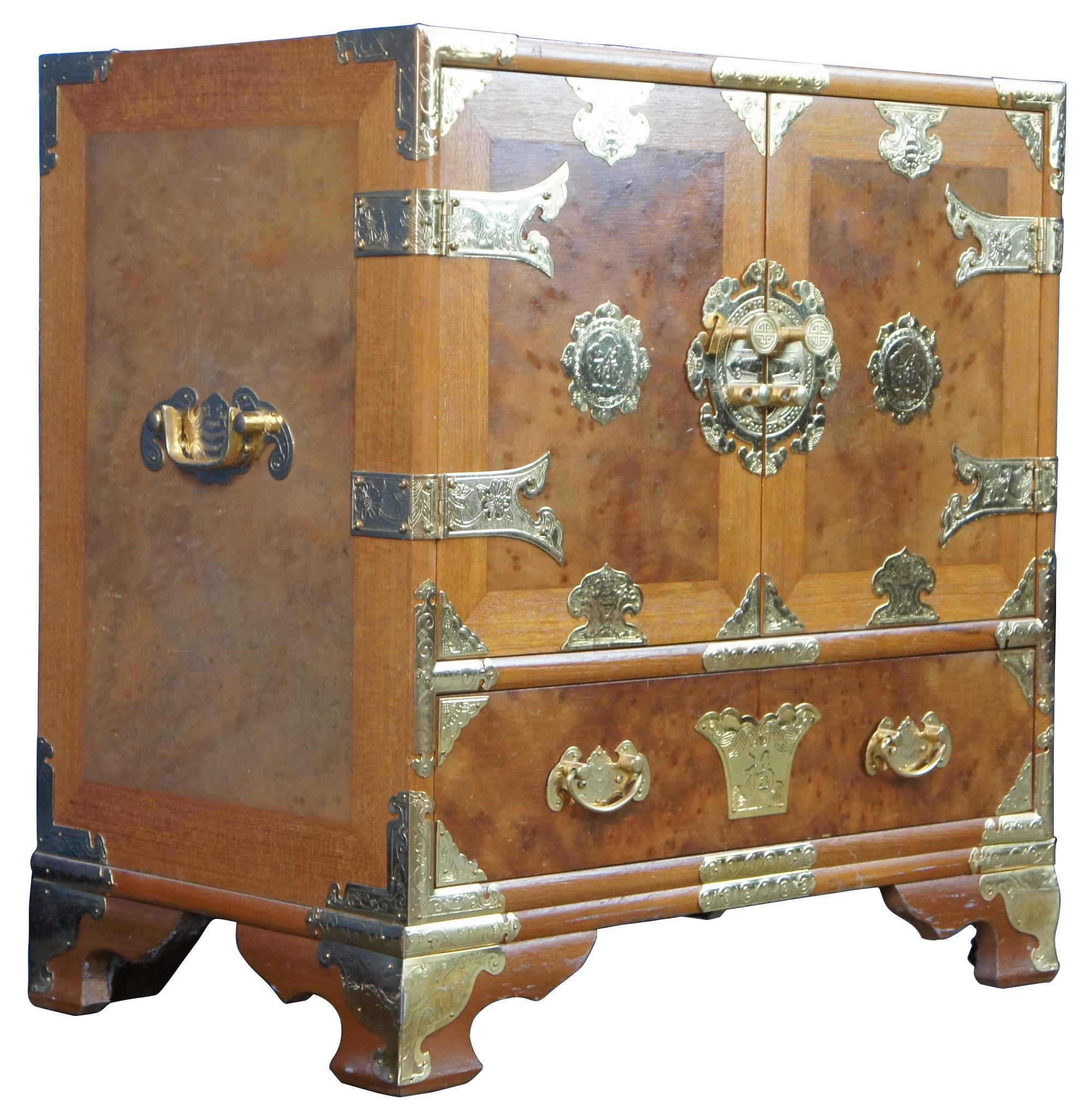 Mid century tansu inspired chest featuring elm burl wood case with a heavy adornment of brass accents.
  