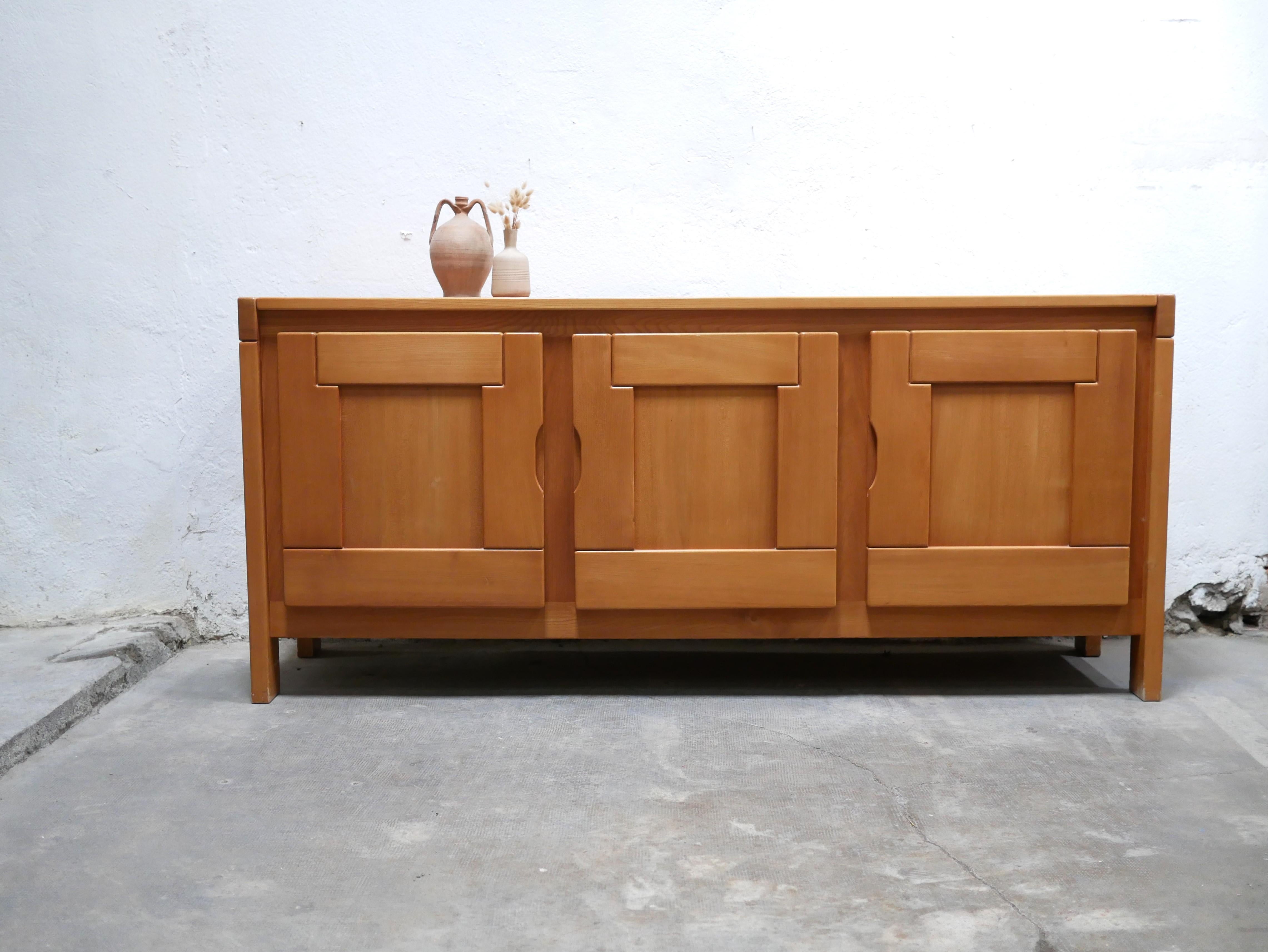 Solid elm sideboard produced by Maison Regain in the 1980s.

The bright, warm color of the wood and its simple, clean lines give it a lot of character and elegance. We love its design, its precious wood and its manufacturing quality.

Timeless, it
