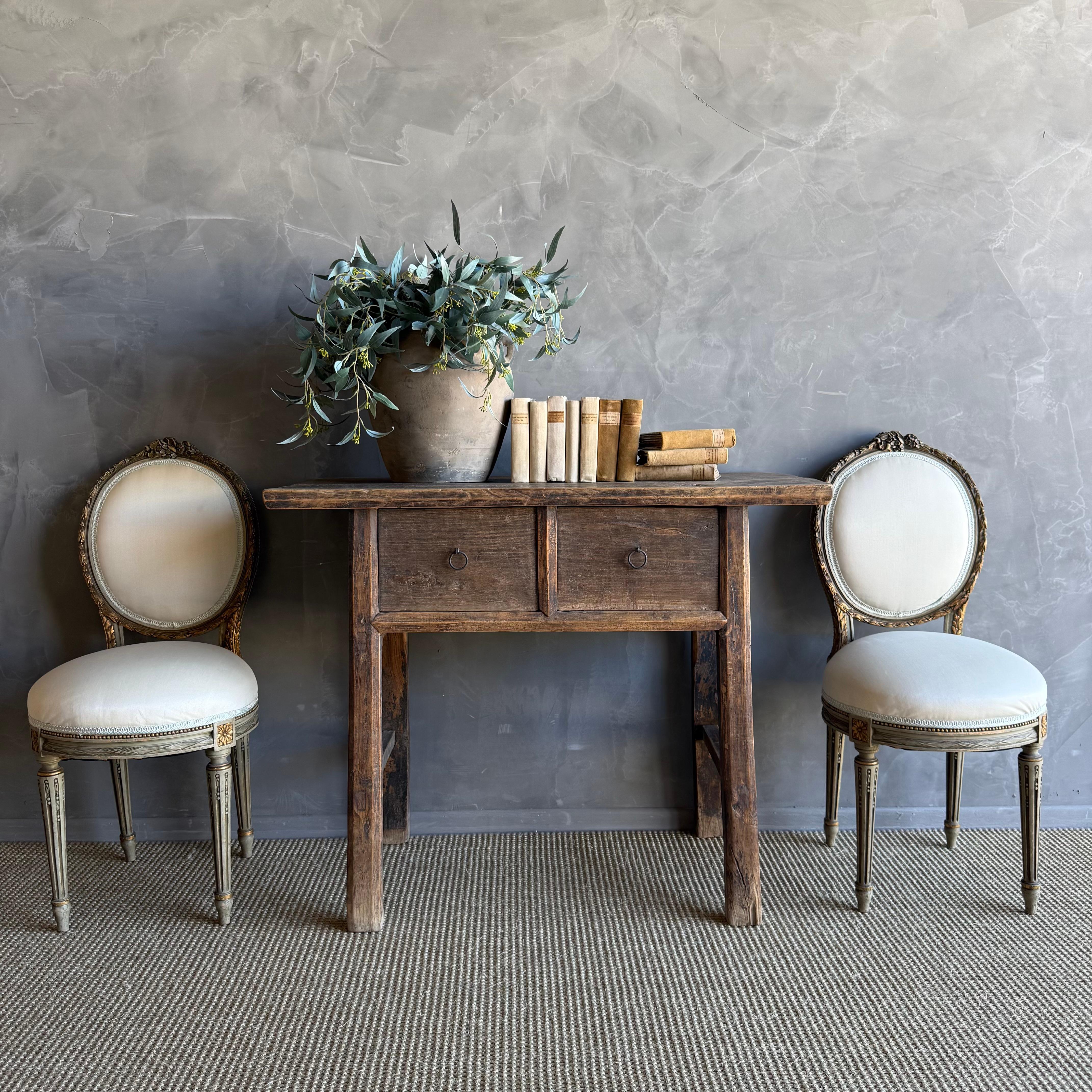 This charming vintage elm wood console is a one-of-a-kind piece with beautiful age and patina that adds character to any space. Its patina painted elm wood finish showcases the natural beauty of the wood, while the solid elm wood original hardware