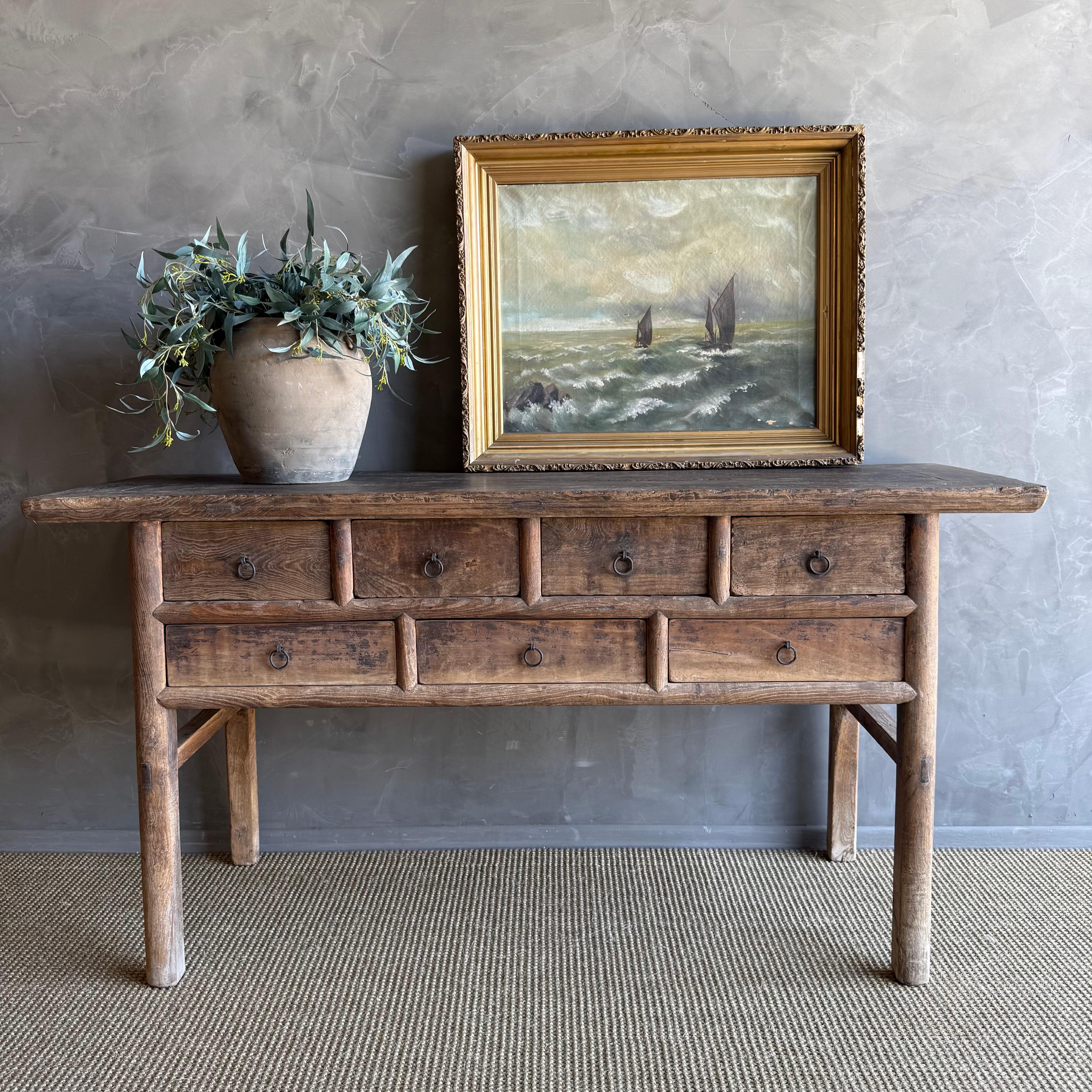 This charming vintage elm wood console is a one-of-a-kind piece with beautiful age and patina that adds character to any space. Its patina painted elm wood finish showcases the natural beauty of the wood, while the solid elm wood original hardware