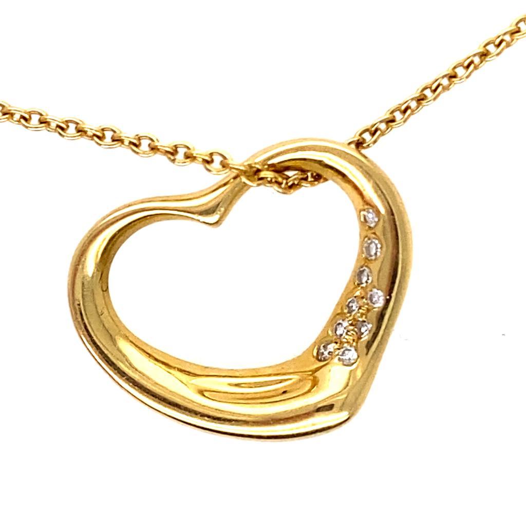 A vintage Elsa Peretti for Tiffany & Co. diamond heart pendant and chain. 

This solid 18 karat yellow gold open heart pendant depicts the simple, evocative Elsa Peretti open heart design, rubover set with nine individual round brilliant cut
