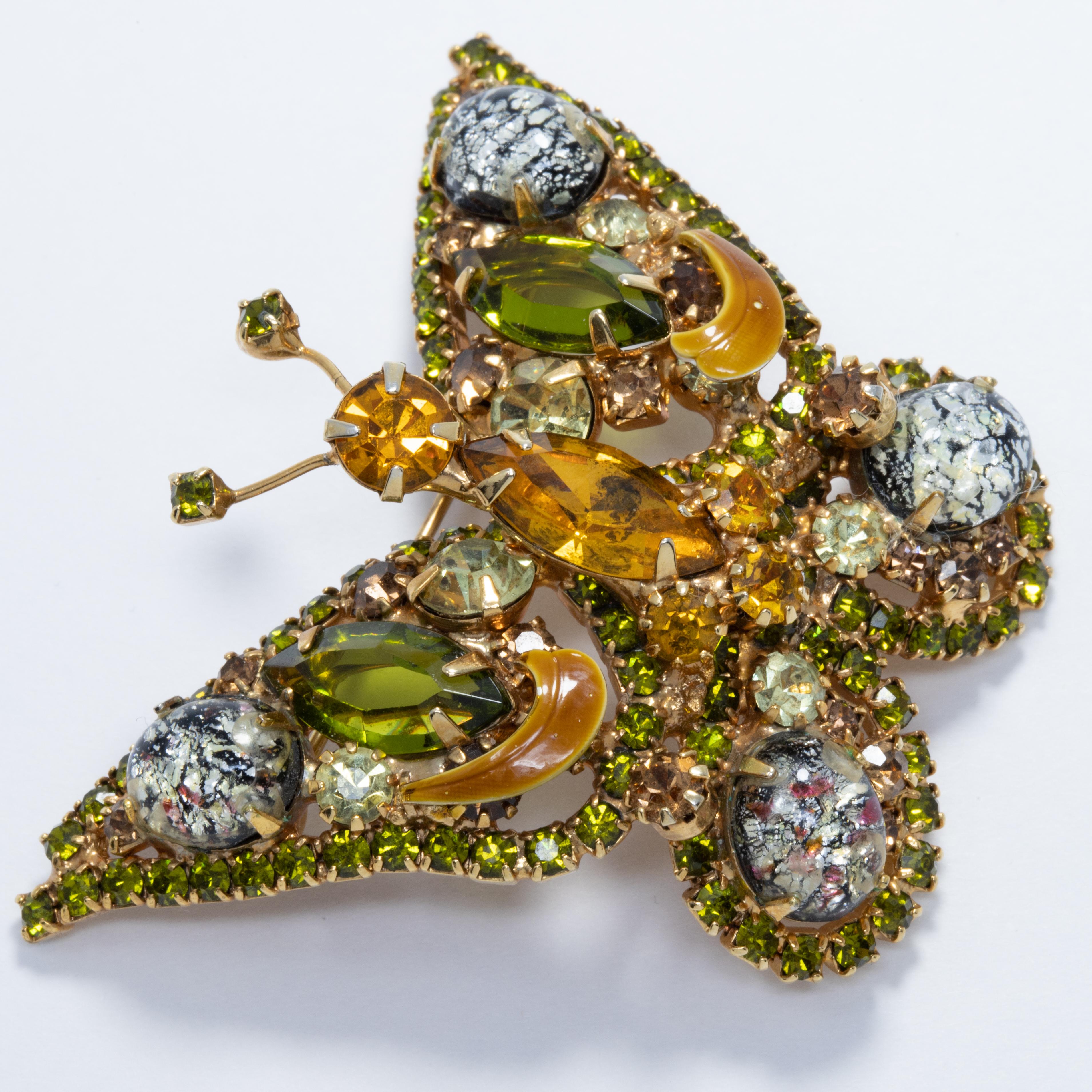 A sparkling butterfly pin brooch decorated with dazzling, prong set crystals. Features glittering white catseye cabochons, as well as olivine, amber, and topaz accents for an exquisite golden look.

Gold tone.