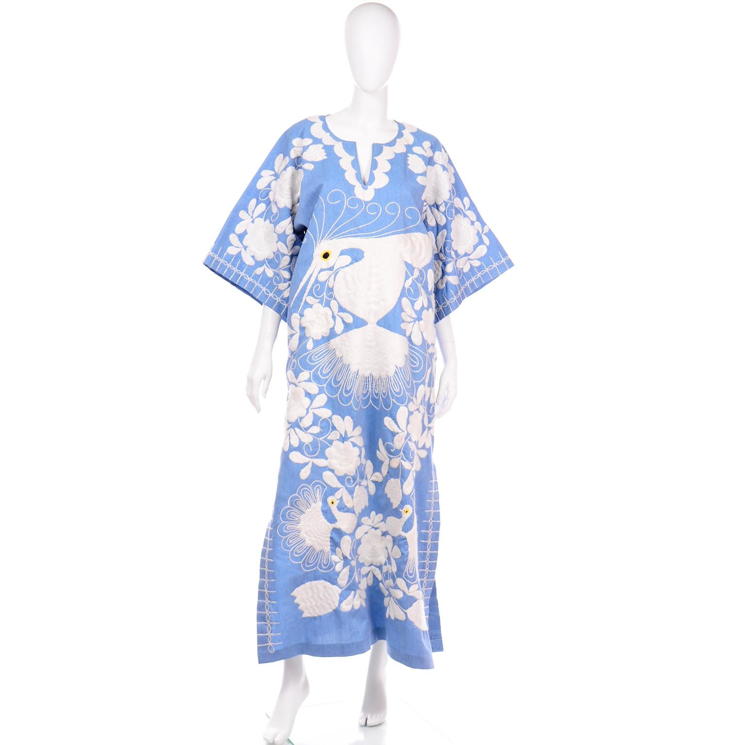 This is a spectacular hand embroidered vintage blue caftan dress with a floral and bird motif. This incredible dress has thick white embroidery and the bird in the center has a yellow and black eye. The sleeves are bell shaped the dress can fit a