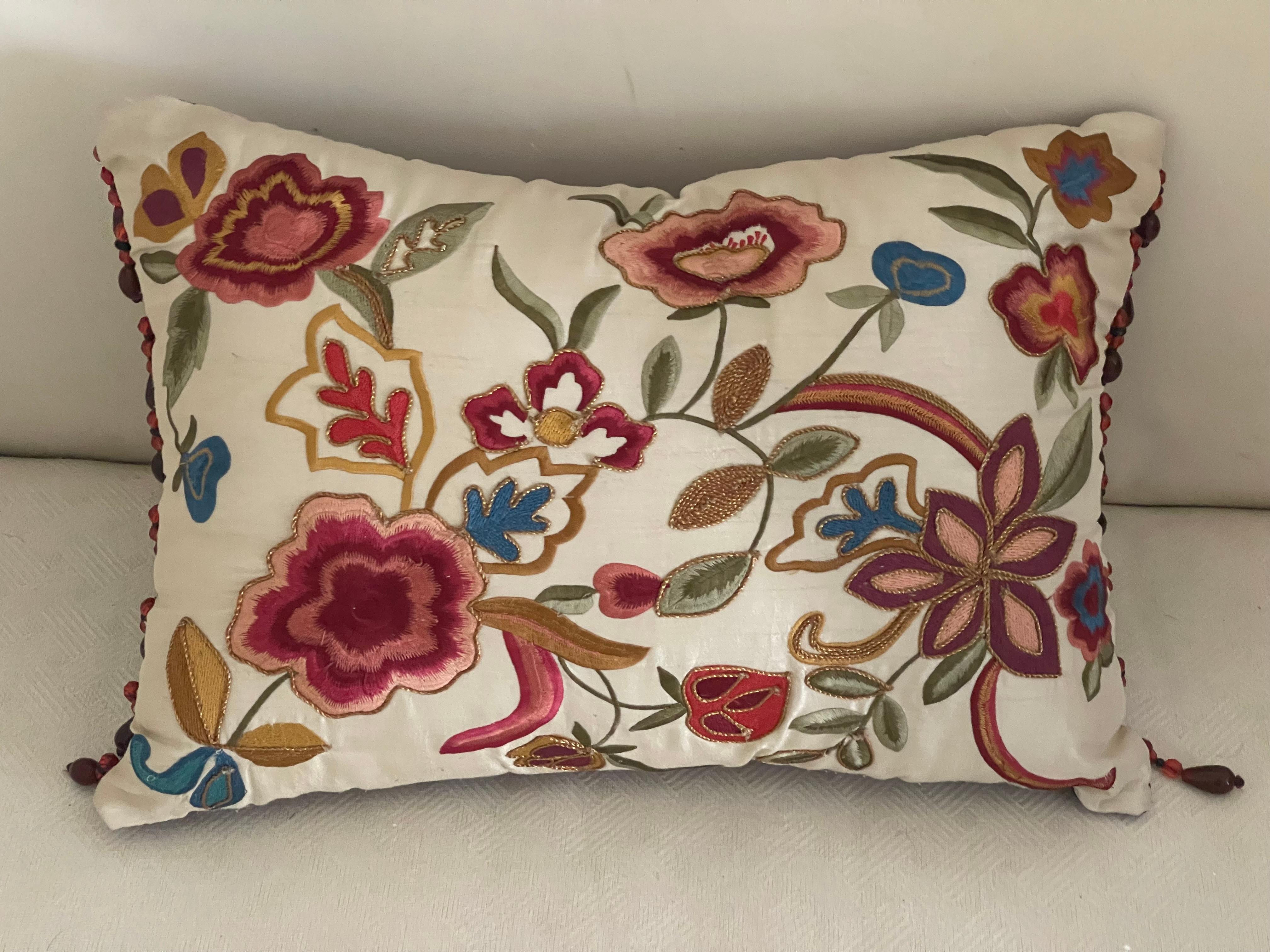 Coussin lombaire en soie florale brodée aux couleurs vives, avec dos rouge vigne et franges perlées rouge vigne.