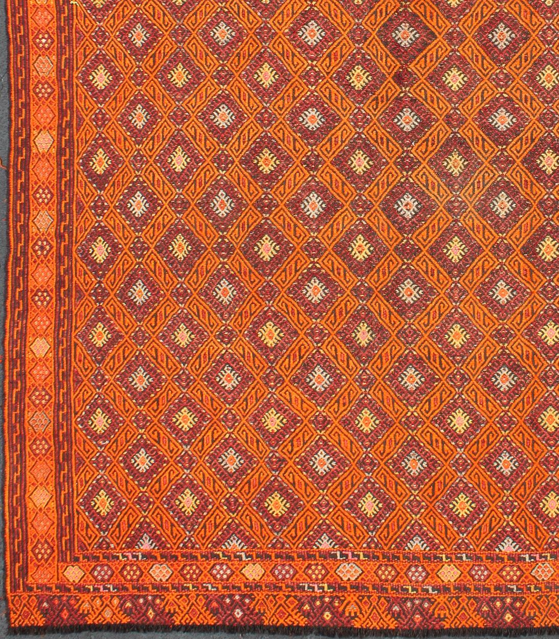 Vintage Embroidered Kilim in Orange, Red, light Blue and yellow Colors.
The simple symmetric diamond form in this piece is a timeless plaid pattern with wide center stripes flanked by linear accents. Their precise intersecting arrangement