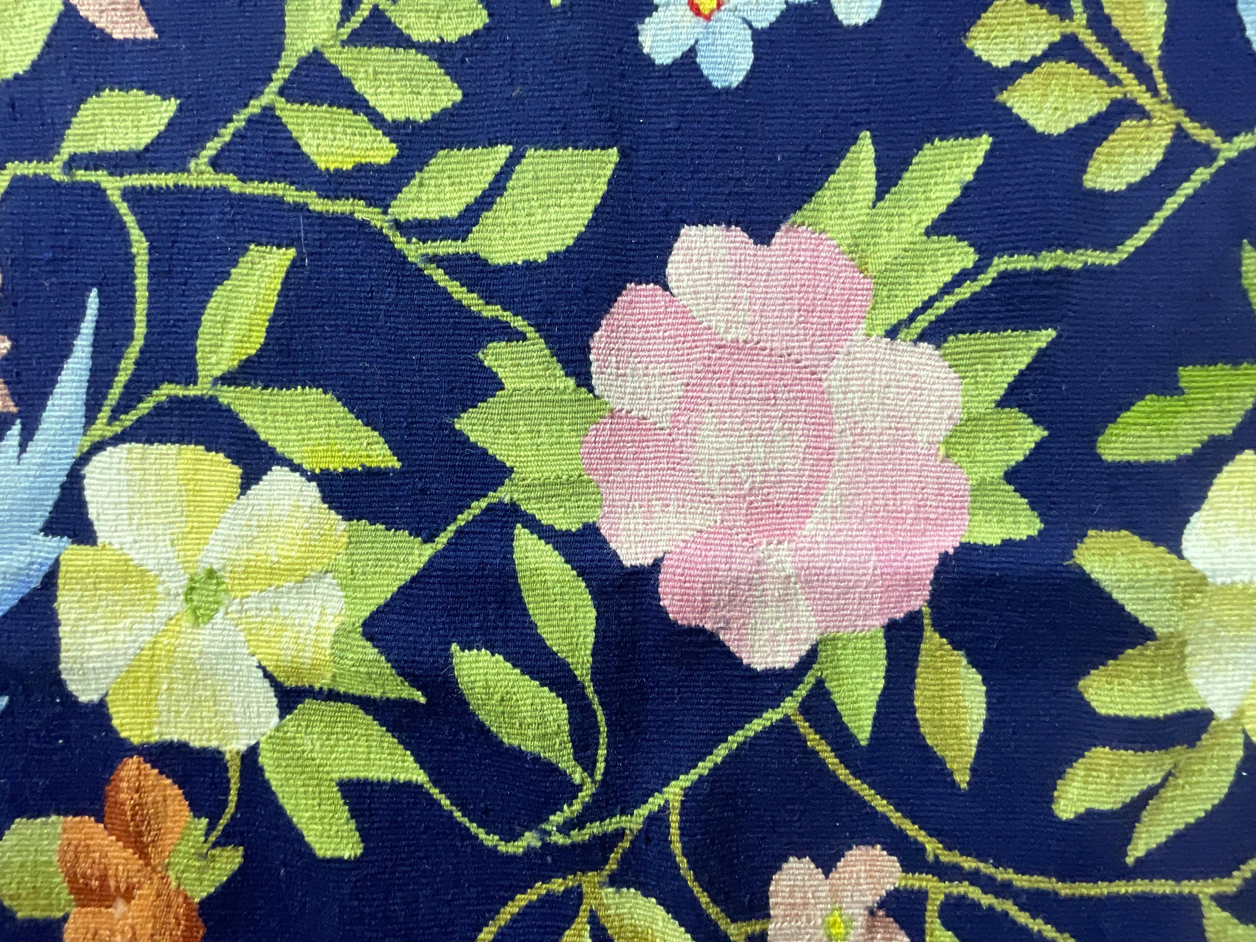 

Este exquisito tapiz o alfombra vintage es una auténtica obra maestra del arte textil. Elaborado con un meticuloso bordado a mano, muestra un vibrante motivo floral y de pájaros sobre un rico fondo azul marino. Los intrincados detalles y los