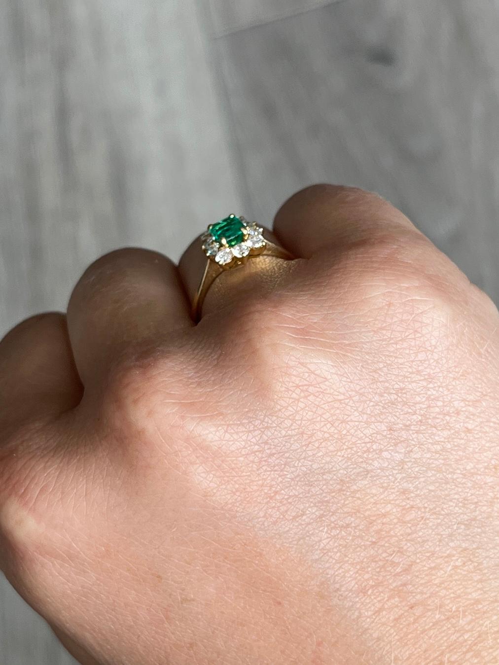 This stunning cluster boasts a 20pt emerald at the centre of it. Surrounding the beautiful green stone are diamonds totalling 50pts. All modelled in 18carat gold.

Ring Size: M or 6 1/4   
Cluster Dimensions: 10x8mm

Weight: 3.2g