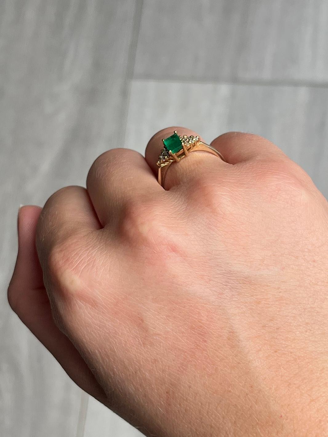 The central emerald is so bright and beautiful and measures 25pts. Sat either side it are six small but shimmering diamond shoulders. The diamonds total approx 6pts. The ring is modelled in 9ct gold.

Ring Size: N or 6 3/4 
Height Off Finger: