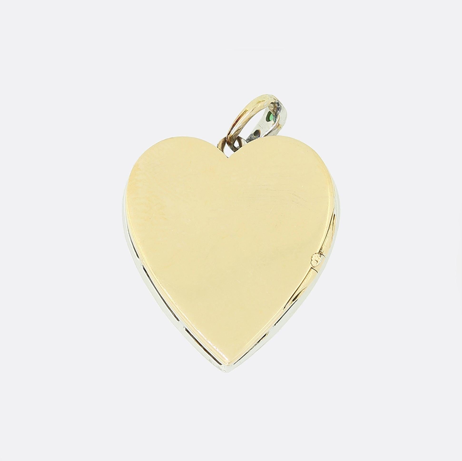This is a lovely 18ct yellow gold emerald and diamond heart pendant. The pendant features a central square cut emerald which is surrounded by an array of old cut diamonds; all of which are set in white gold. The rich green of the emerald is highly