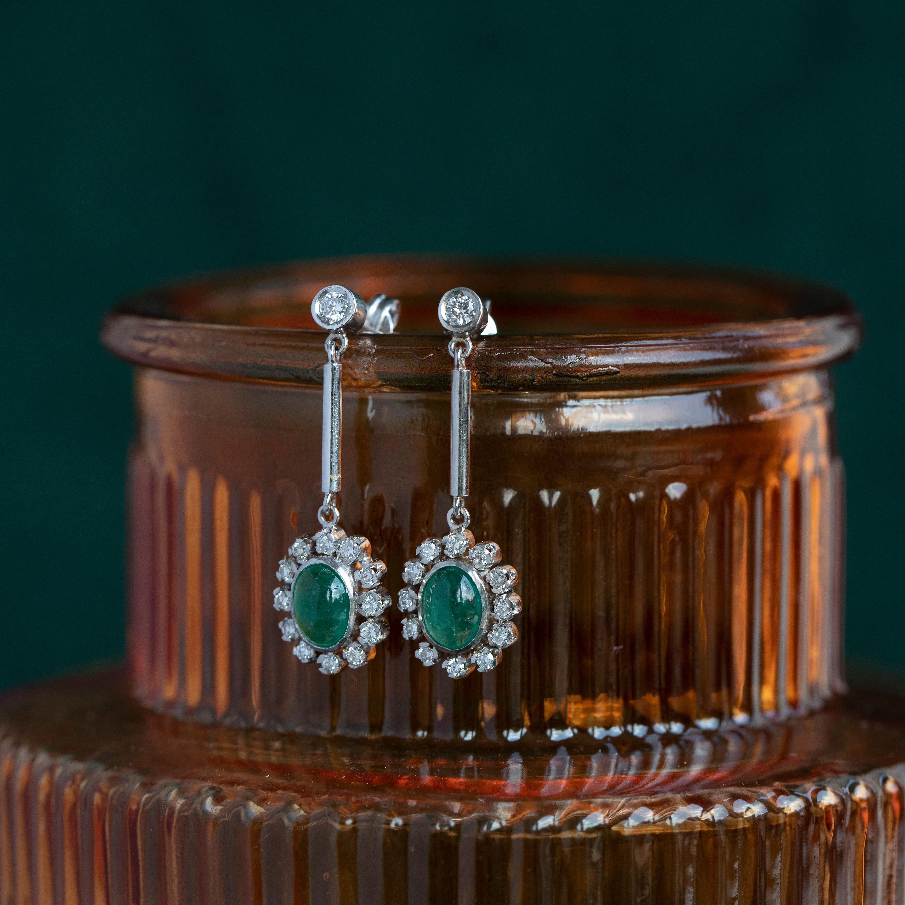 Vibranti e verdeggianti smeraldi cabochon sono incastonati in prezioso platino, circondati da oltre 1/2 carato di diamanti brillanti e scintillanti in questi orecchini pendenti di metà secolo. 

 Gli smeraldi sono tra le pietre preziose più