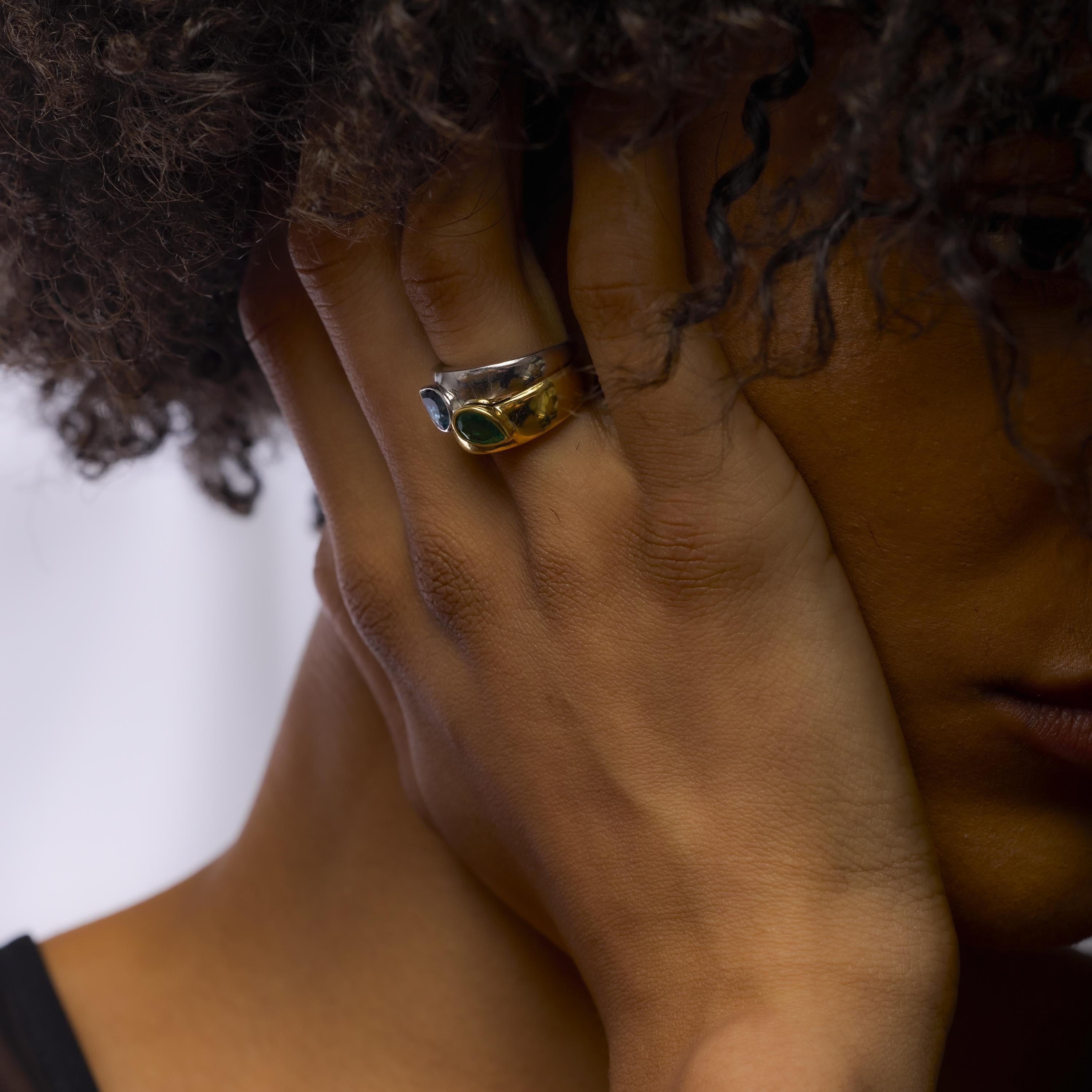 Cette bague vintage associe une émeraude en forme de poire et une aigue-marine en or jaune et blanc 18 carats, pour un design frappant et coloré.