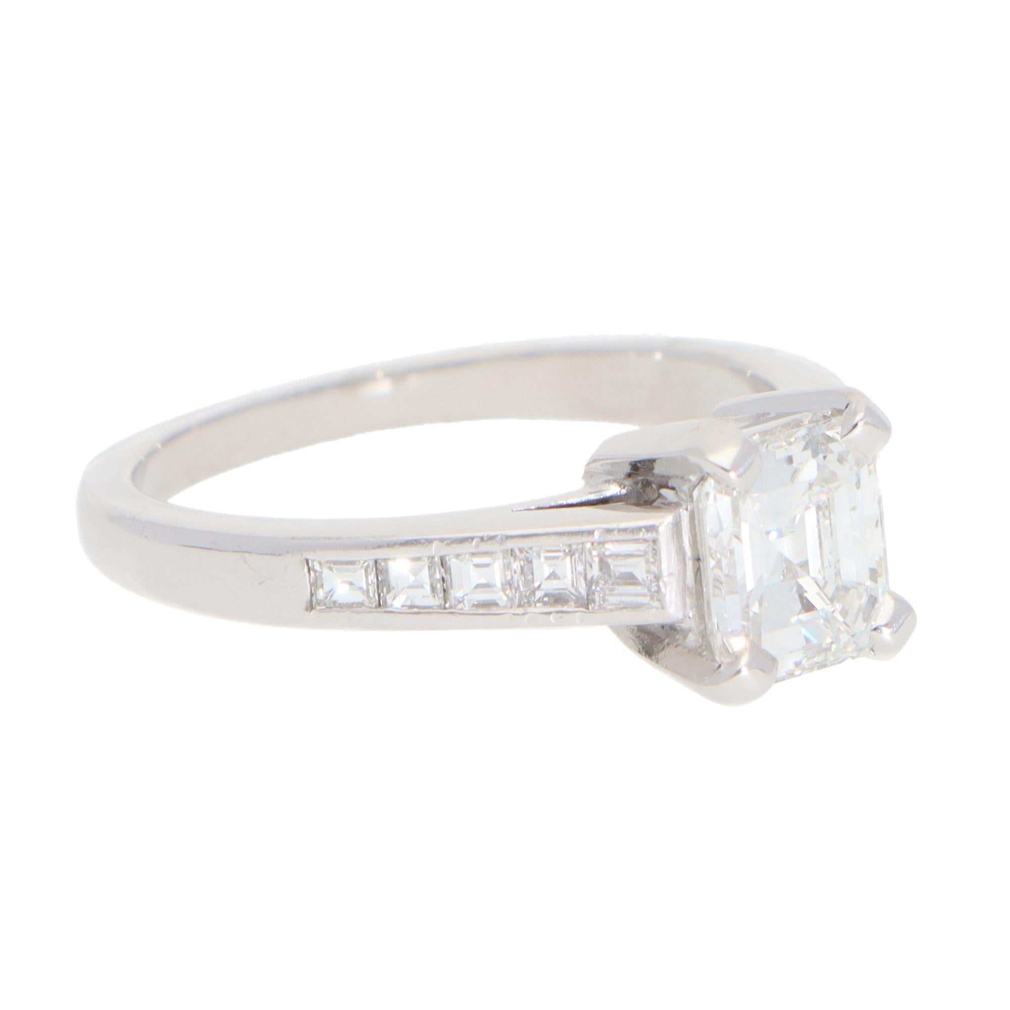 A beautiful vintage emerald-cut diamond ring set in platinum.

The ring is predominantly set with a sparkly emerald-cut diamond in a four-prong setting. Beside this beautiful diamond, 10 square step-cut diamonds flow round nicely to the shoulders of