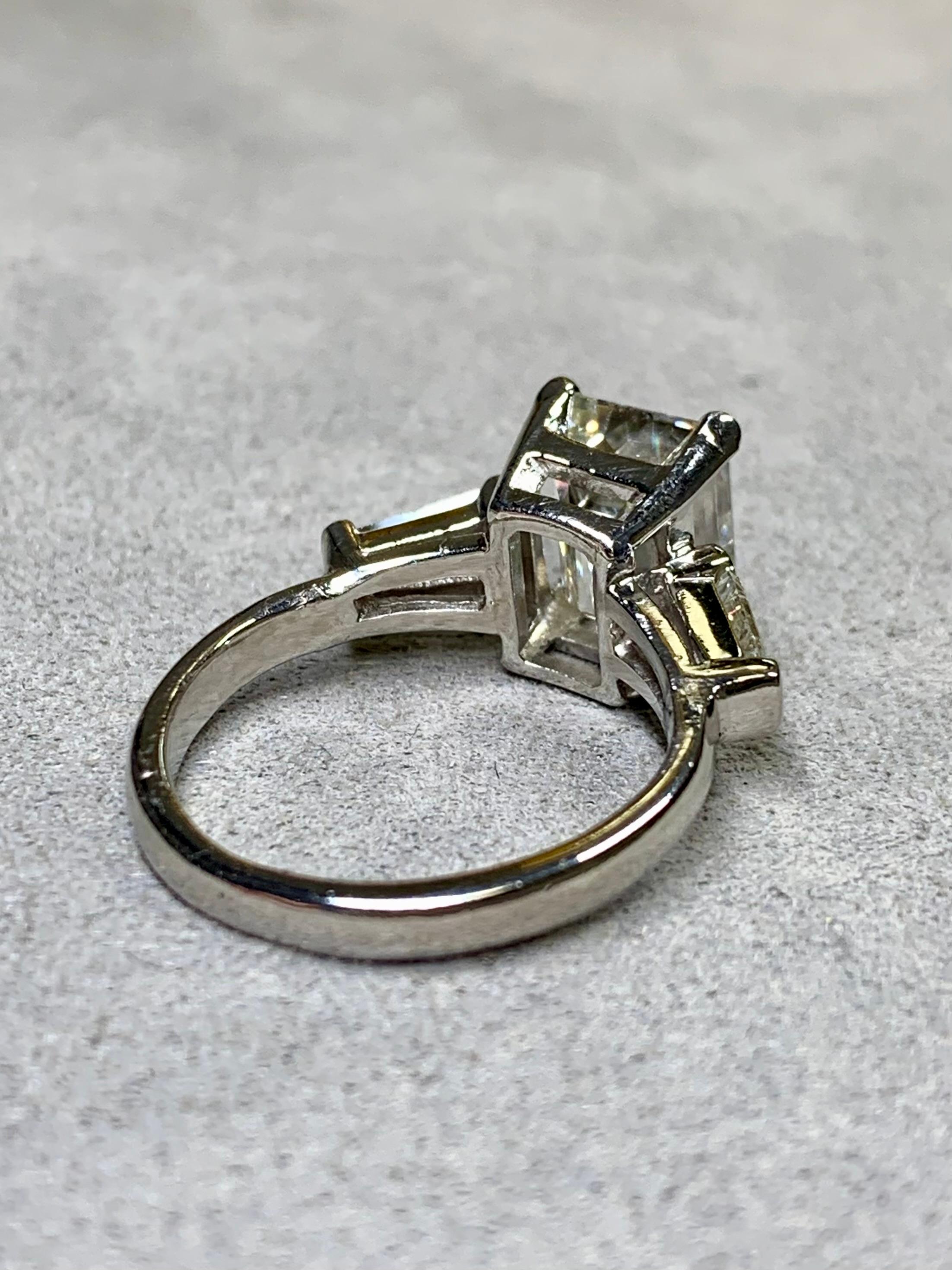 A classic engagement ring circa of the 1960s done platinum and centered by a 3.64ct emerald cut being J in color and Si1 in clarity (completely eye-clean). The Centerstone is flanked by two tapered baguette cut diamonds, both being a matching I-J in